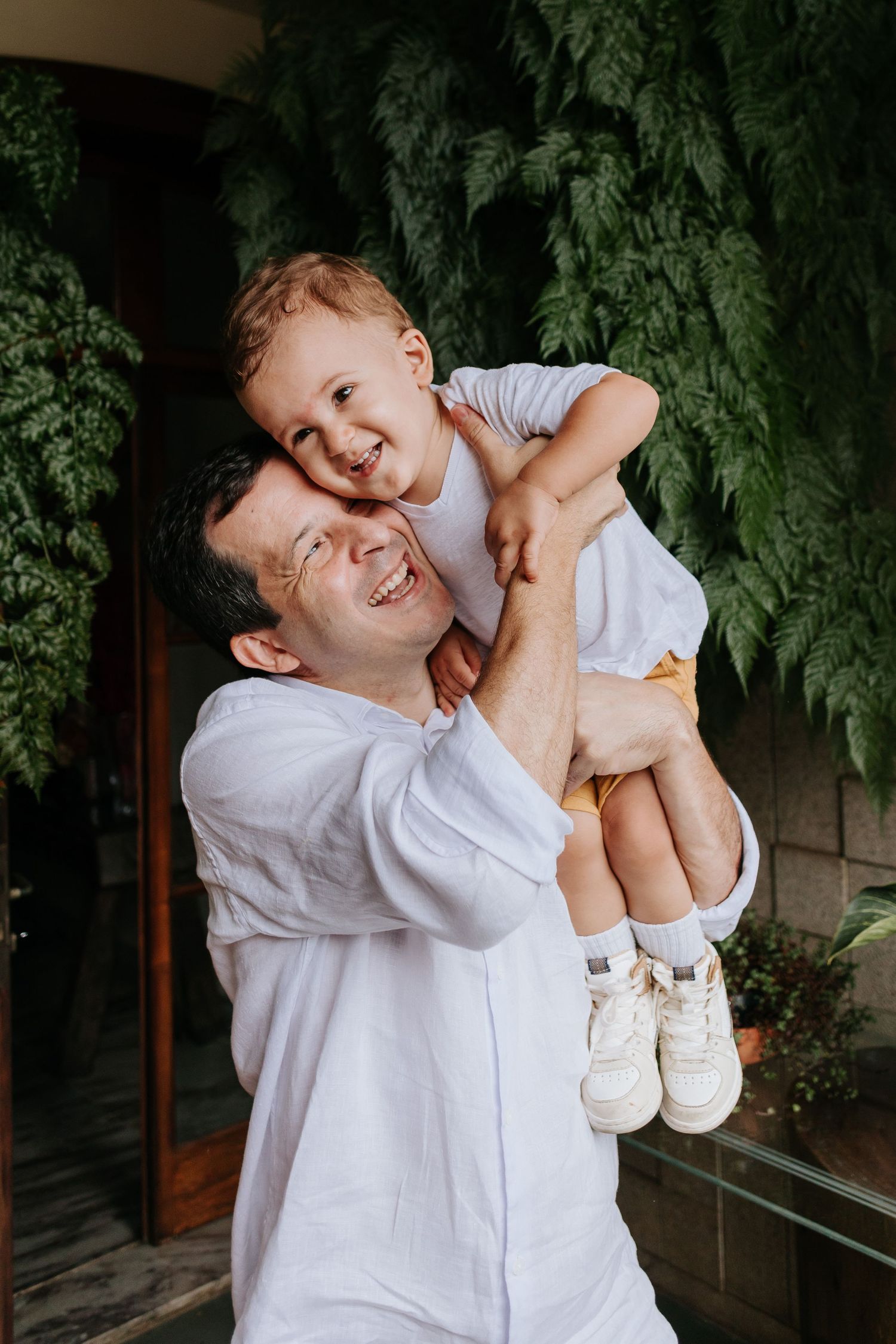 A joyful moment between parent and child playing outdoors among green foliage.