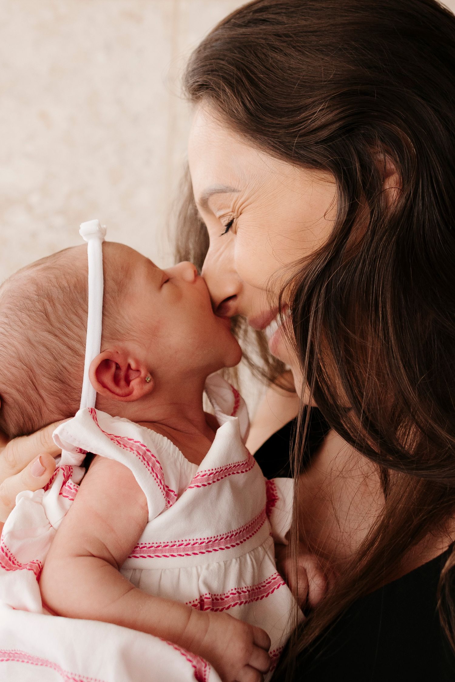 Sweet close-up of parent and baby in white dress sharing an affectionate moment.