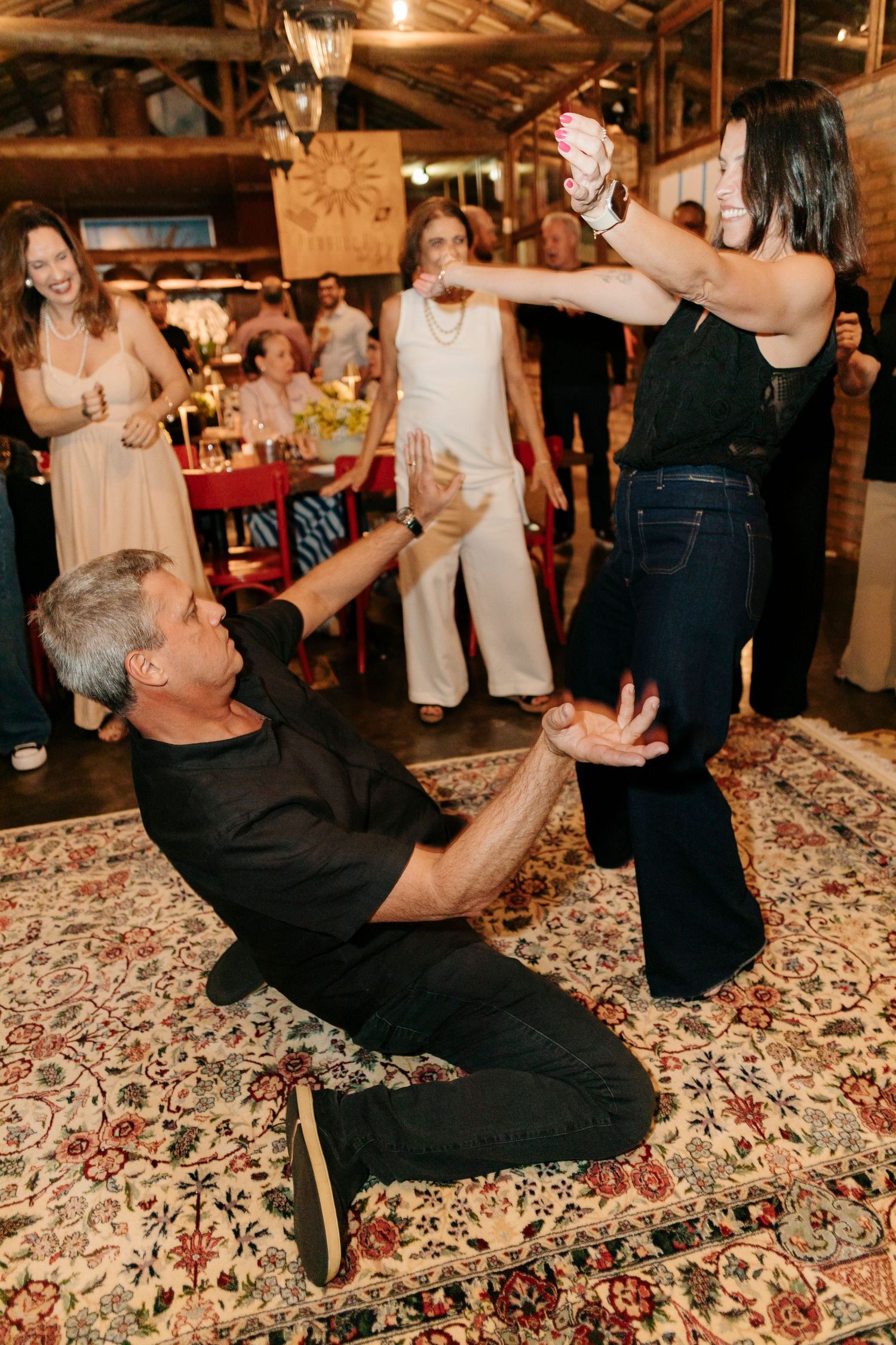 Dancers execute an energetic dance move during a lively indoor celebration.
