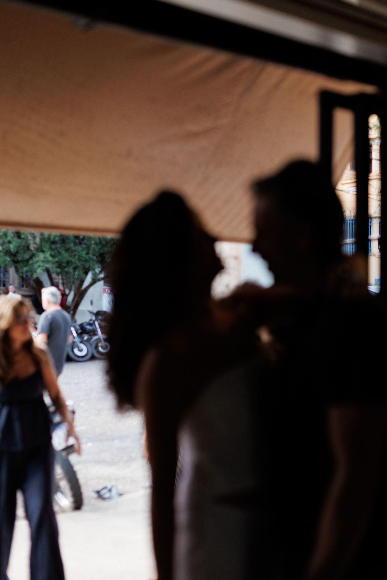 Silhouettes of a couple embracing inside a venue with motorcycles and people visible in the background.