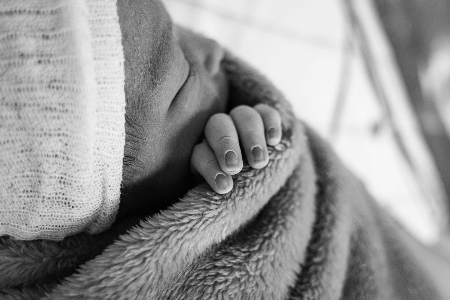 Close up of tiny newborn foot resting on soft blanket in black and white.