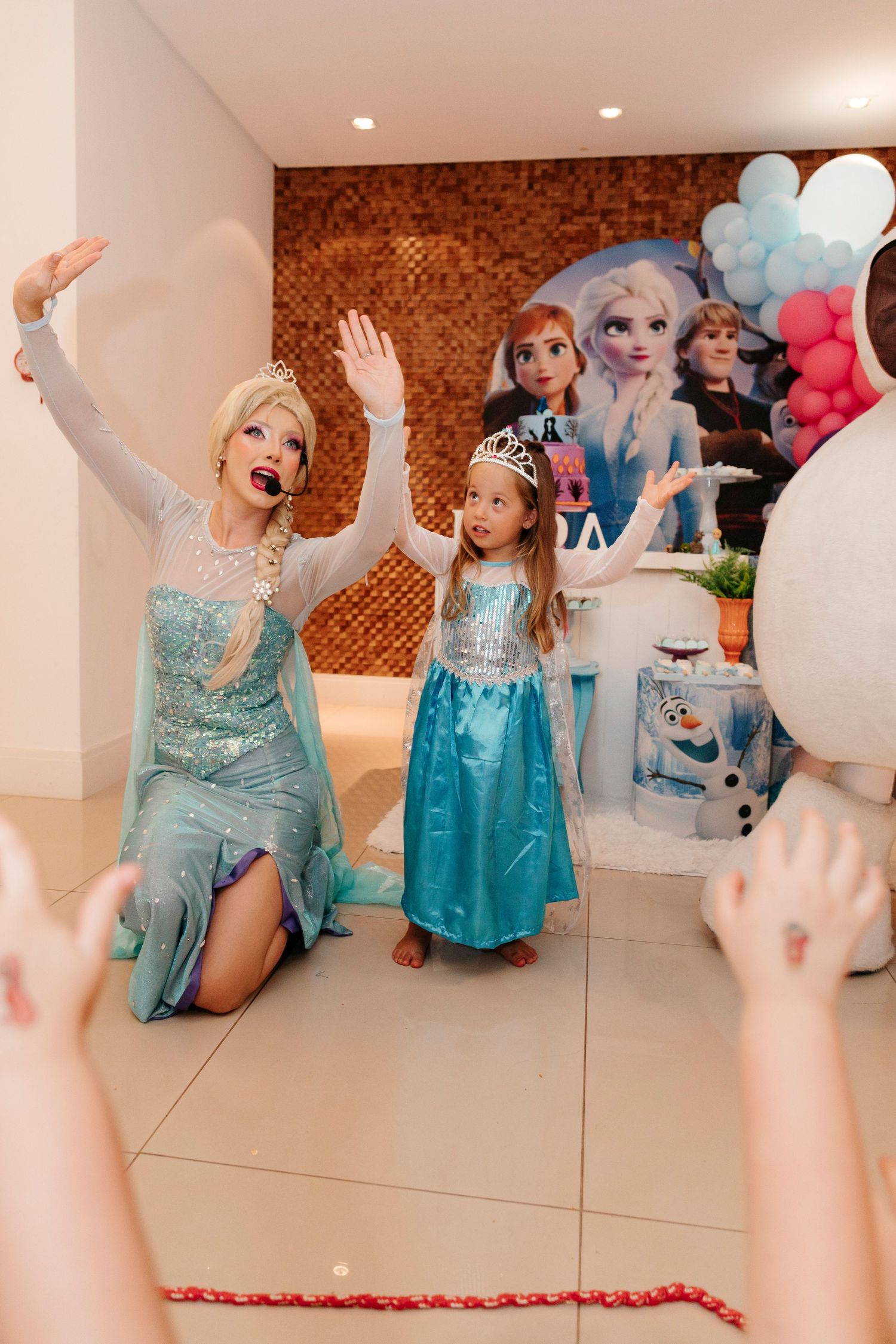 Frozen-themed party with performers and guest in matching blue princess costumes.