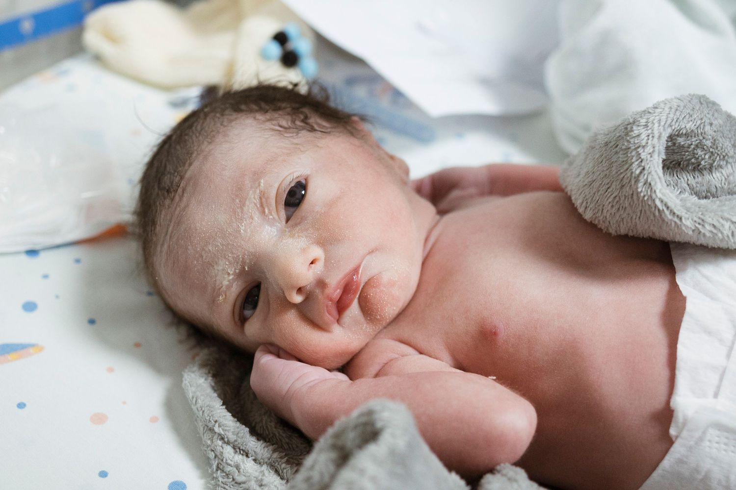 Alert newborn baby lying on hospital blanket after birth.