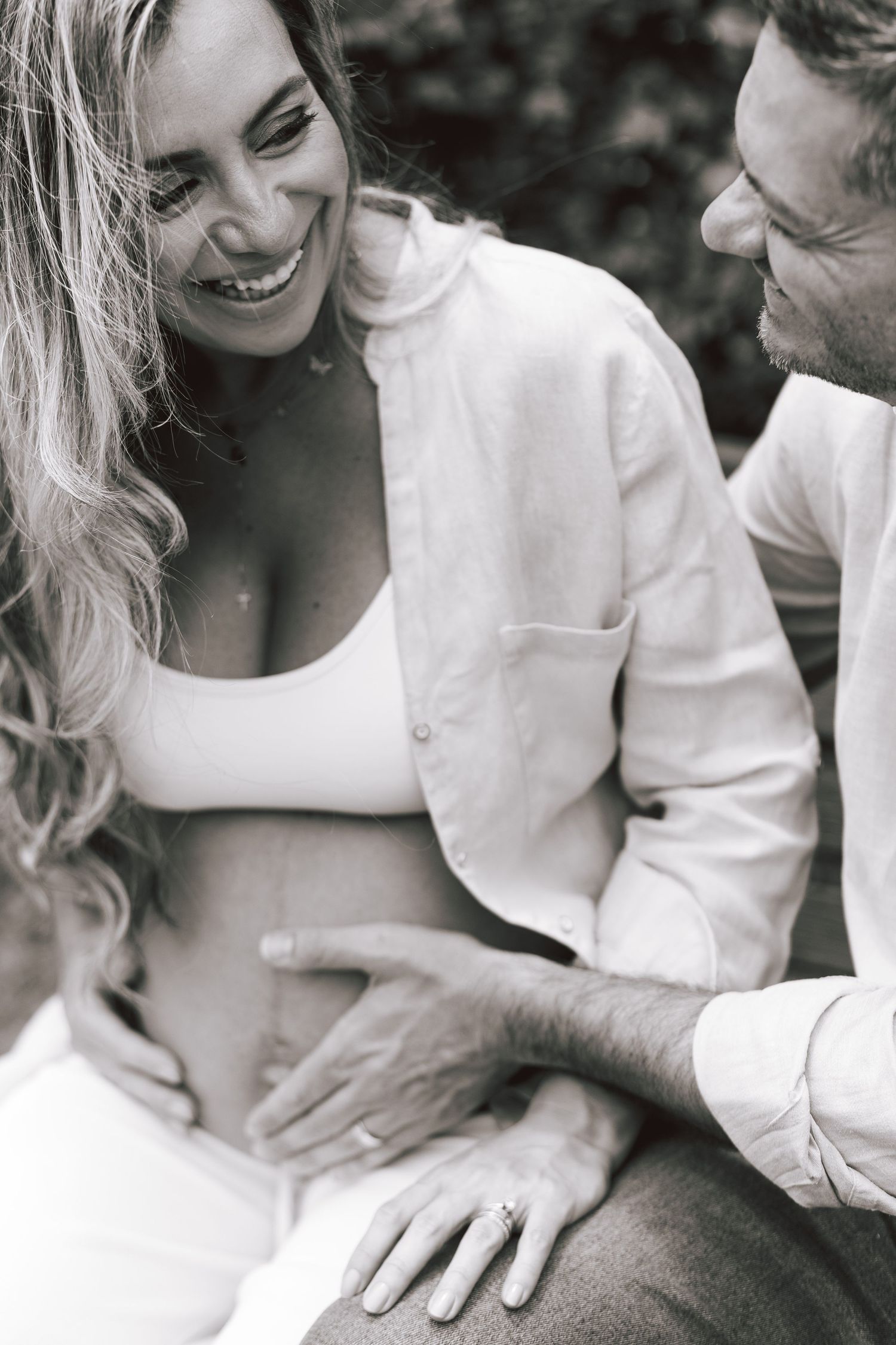 Black and white intimate photo of a couple sharing a joyful moment together as they laugh and embrace.