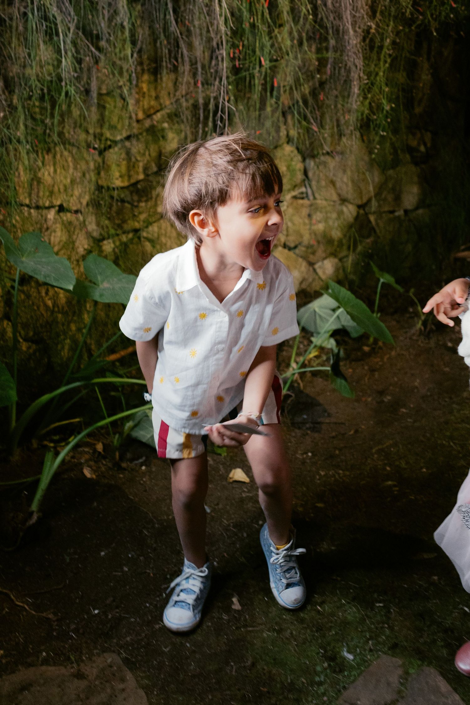 Series of photos showing a child in white exploring and playing in a garden or outdoor space.