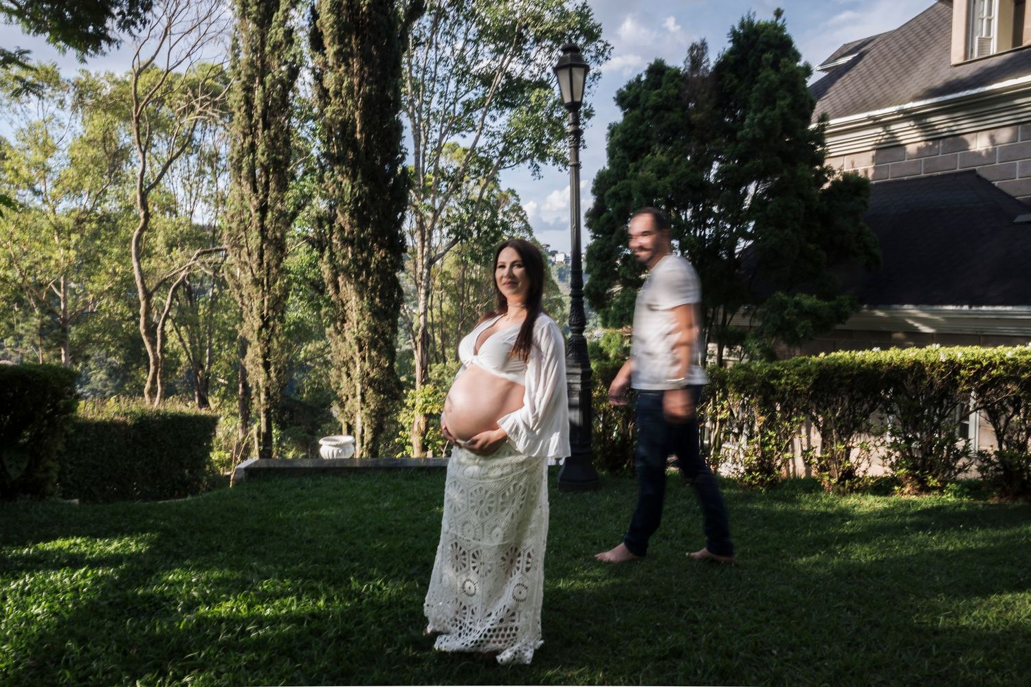 Couple poses together in a garden setting during maternity photoshoot.