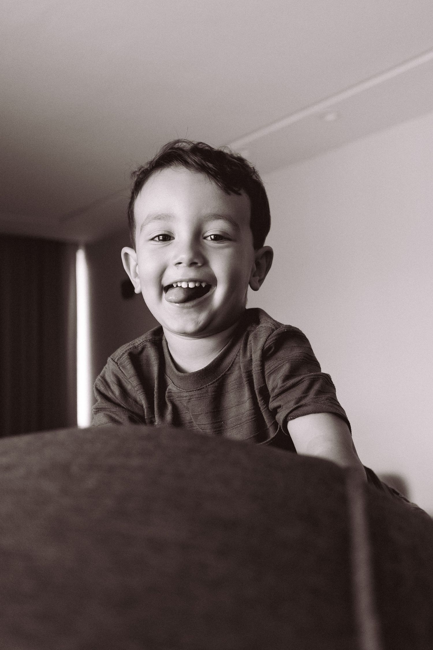 A happy young boy laughs joyfully in a black and white portrait photo.