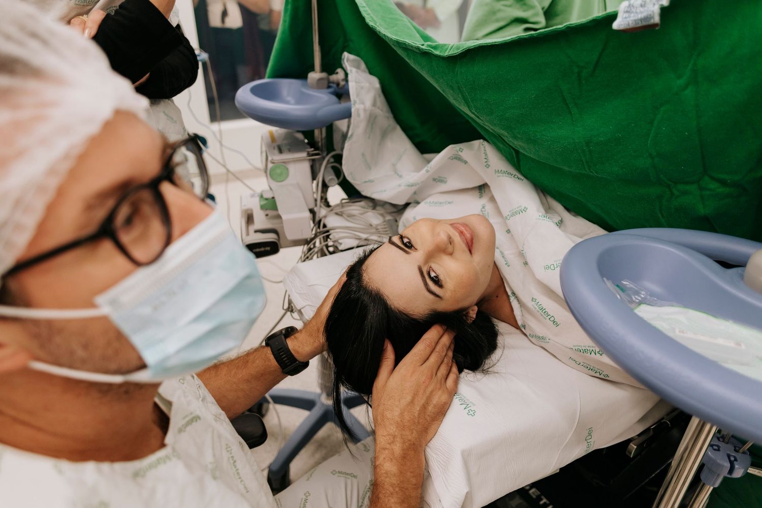Medical professional wearing protective mask examines patient during a healthcare procedure.