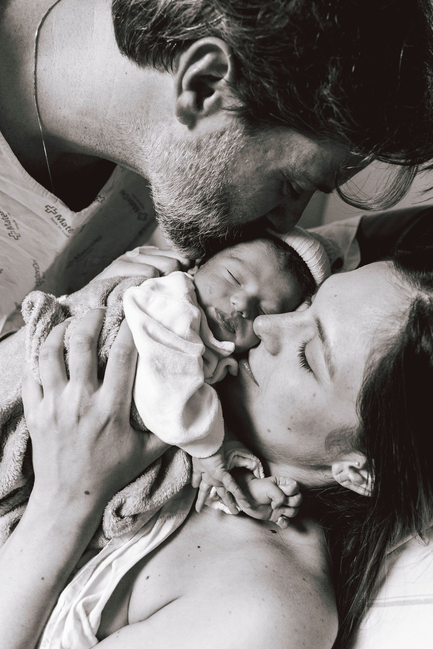 Intimate black and white photo of parents sharing first moments with their newborn.