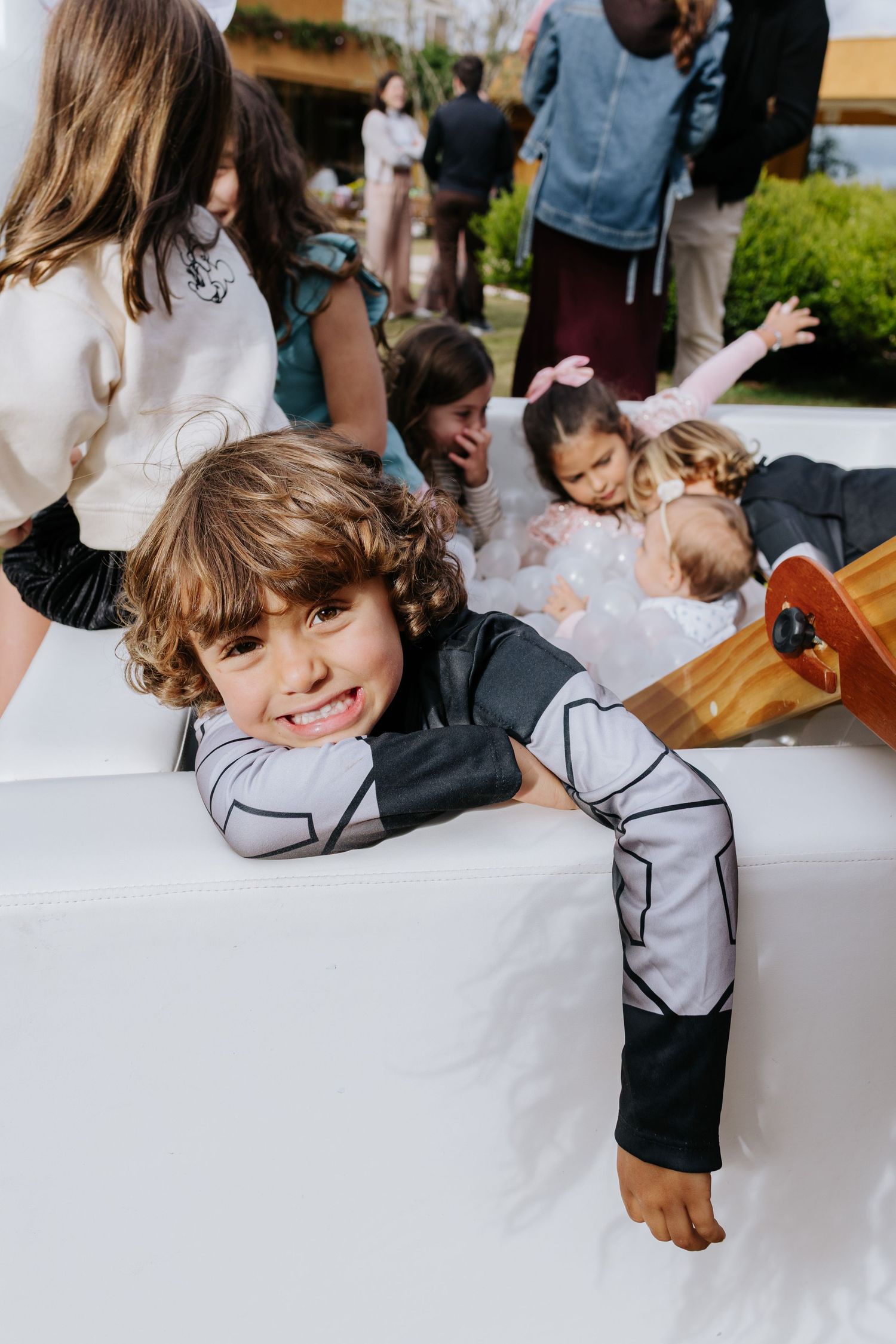 Children in formal attire write and draw on a long white paper roll during what appears to be a wedding reception.