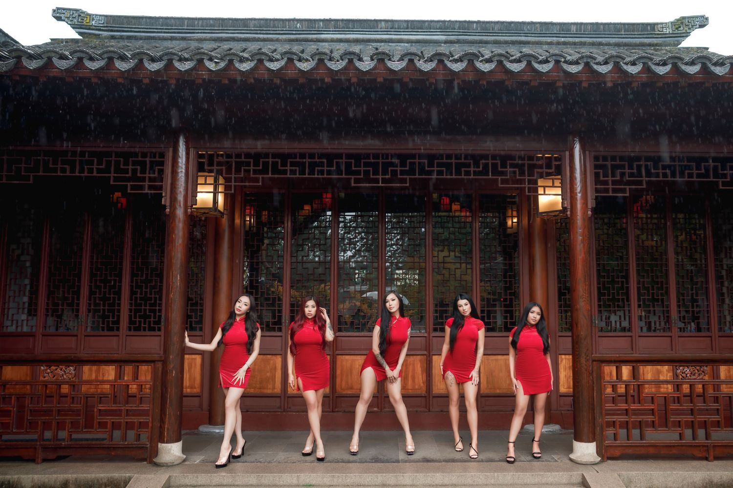 Group photo of women in matching red dresses posing in front of traditional Chinese architecture.