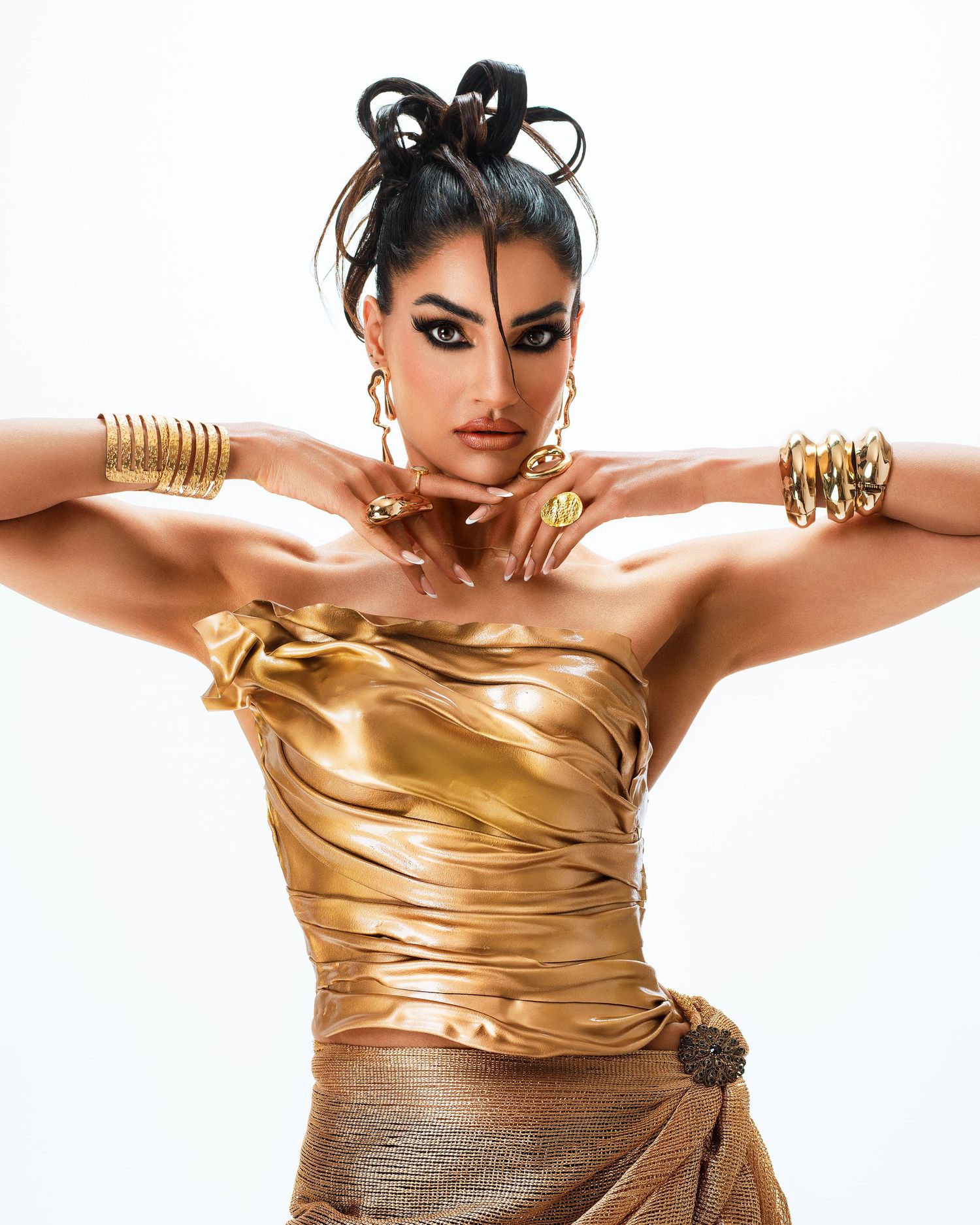 High fashion portrait in metallic gold dress with statement jewelry and dramatic makeup.