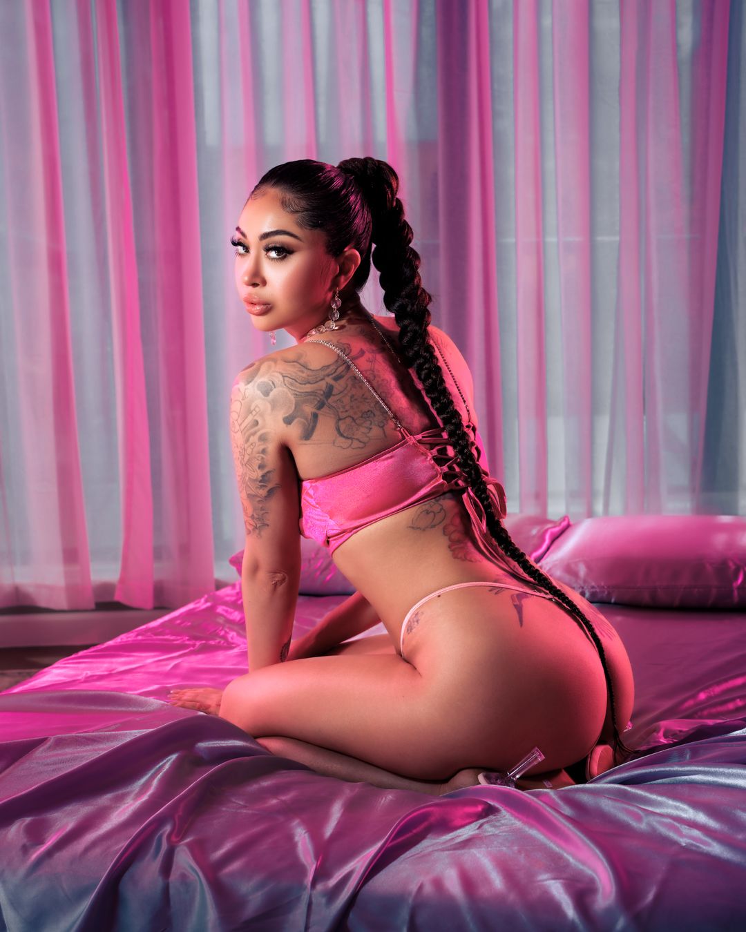 Pink boudoir photography set with dramatic lighting and satin bedding.