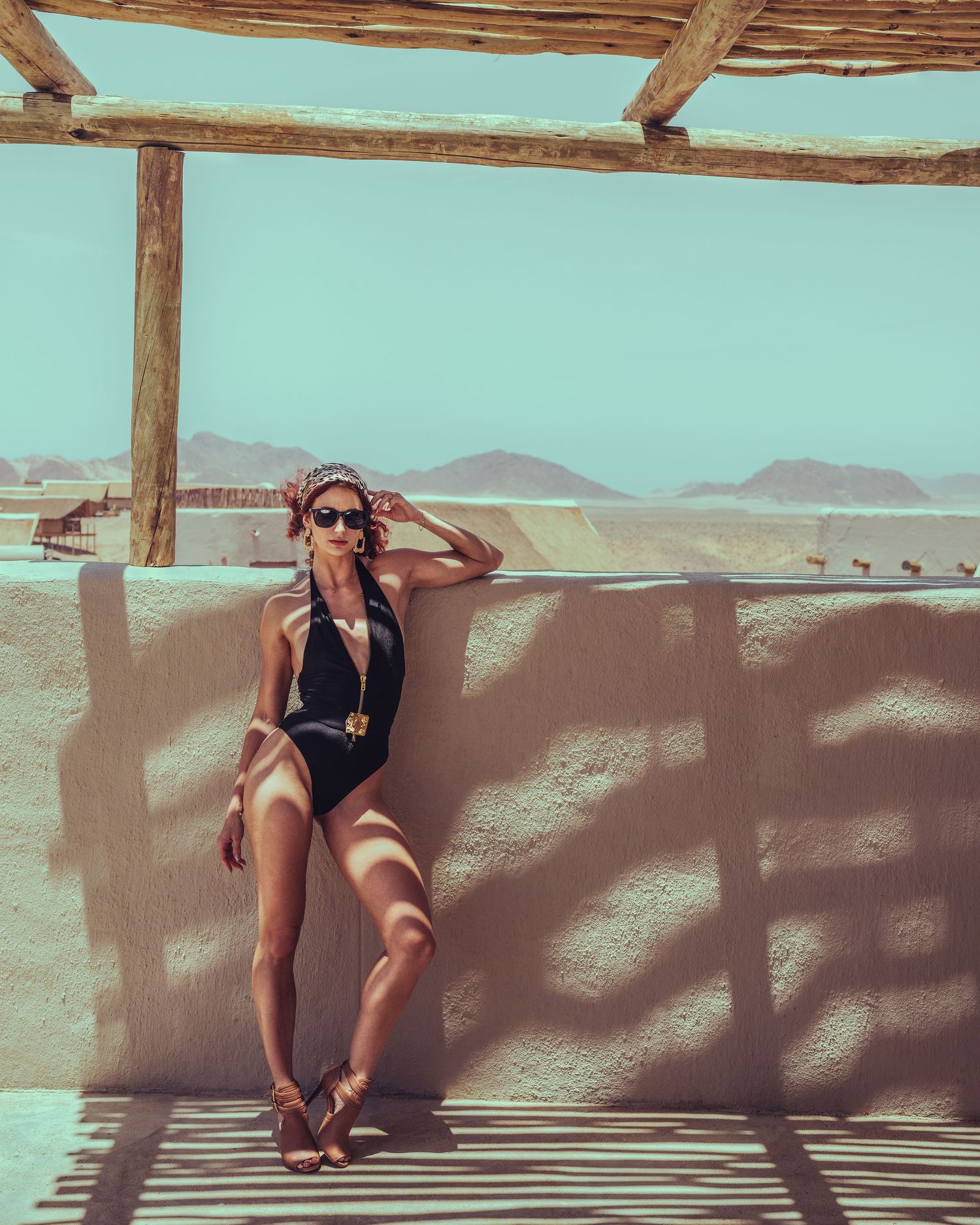 Summer fashion shoot under rustic wooden pergola with desert mountains in background.