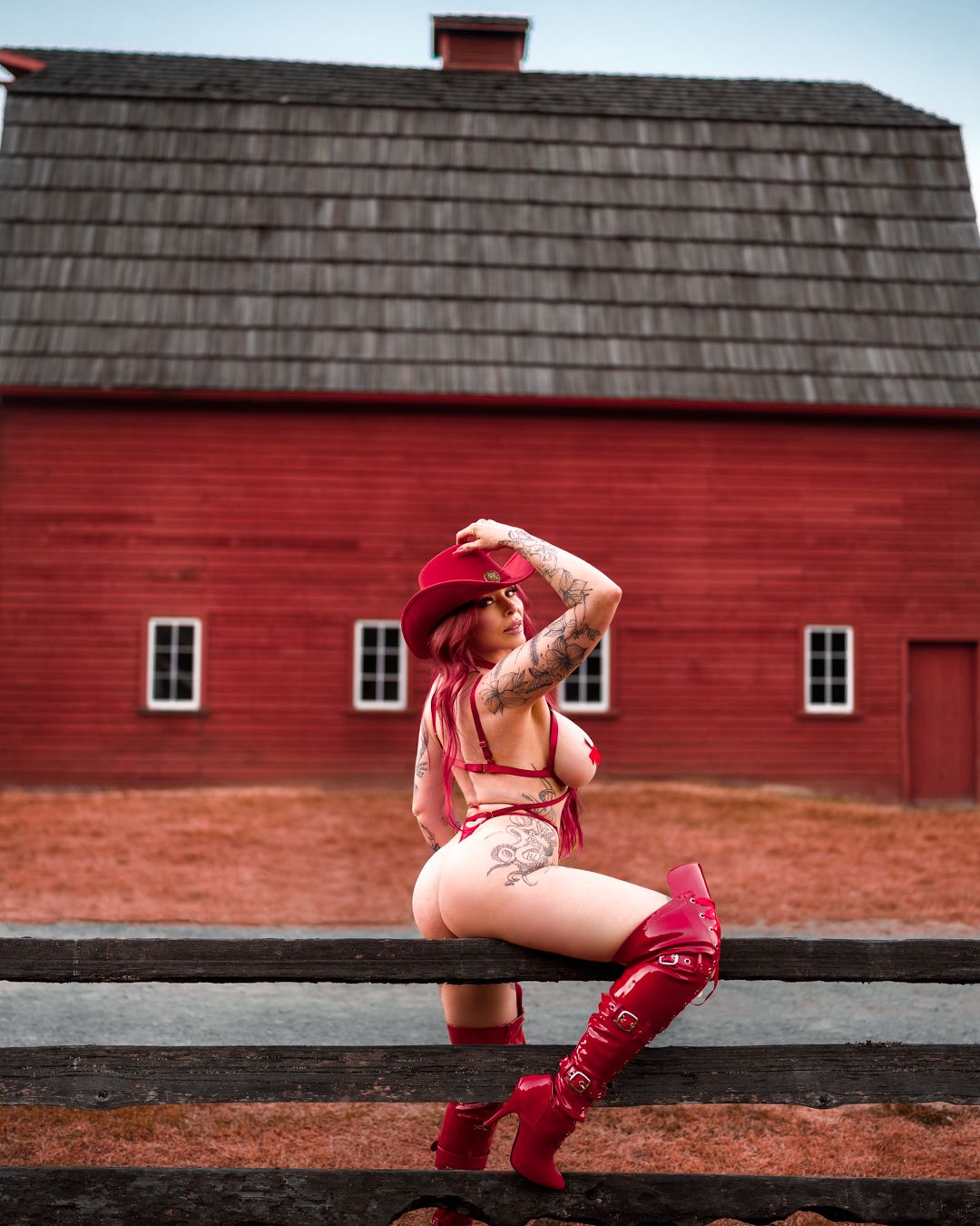 Fashion shot against red barn with wooden shingle roof in rustic setting.