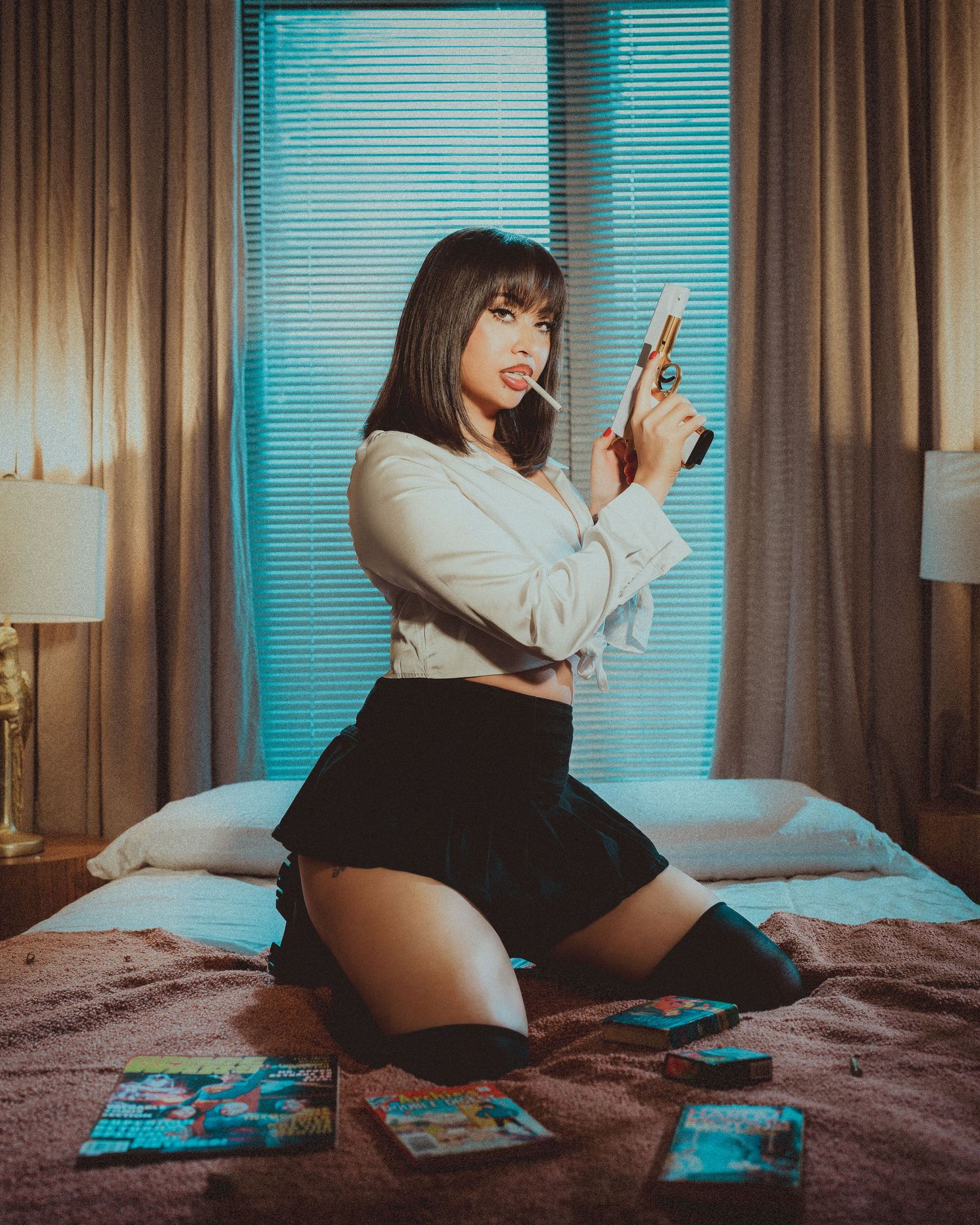 A person in business attire kneels on a bed holding a prop gun in a film noir style scene.