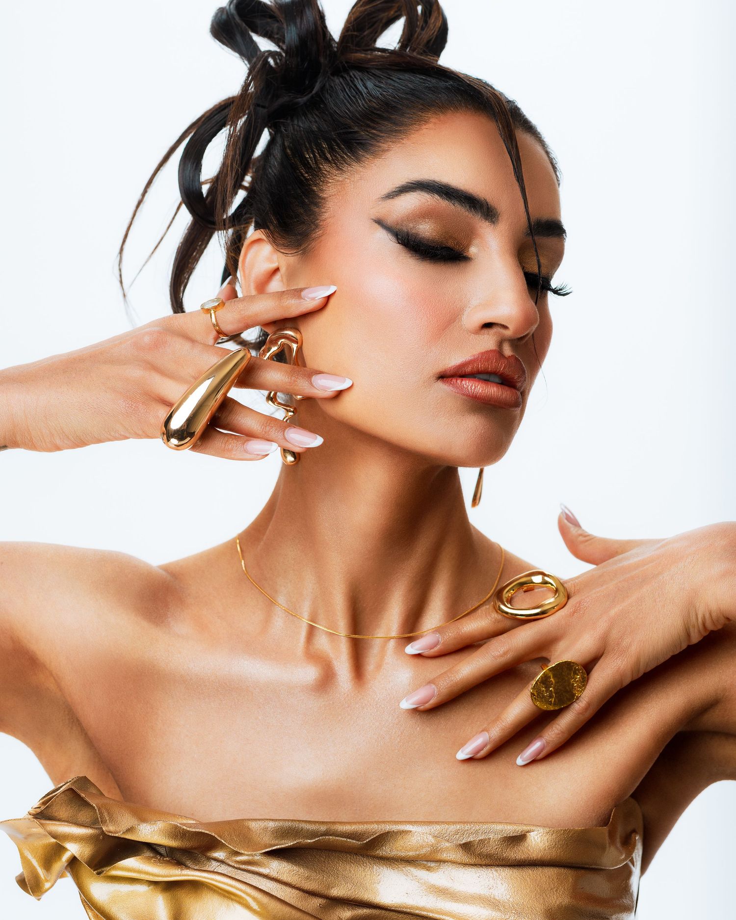 Beauty editorial photo showing a person wearing gold jewelry and red lipstick in a glamorous beauty portrait.