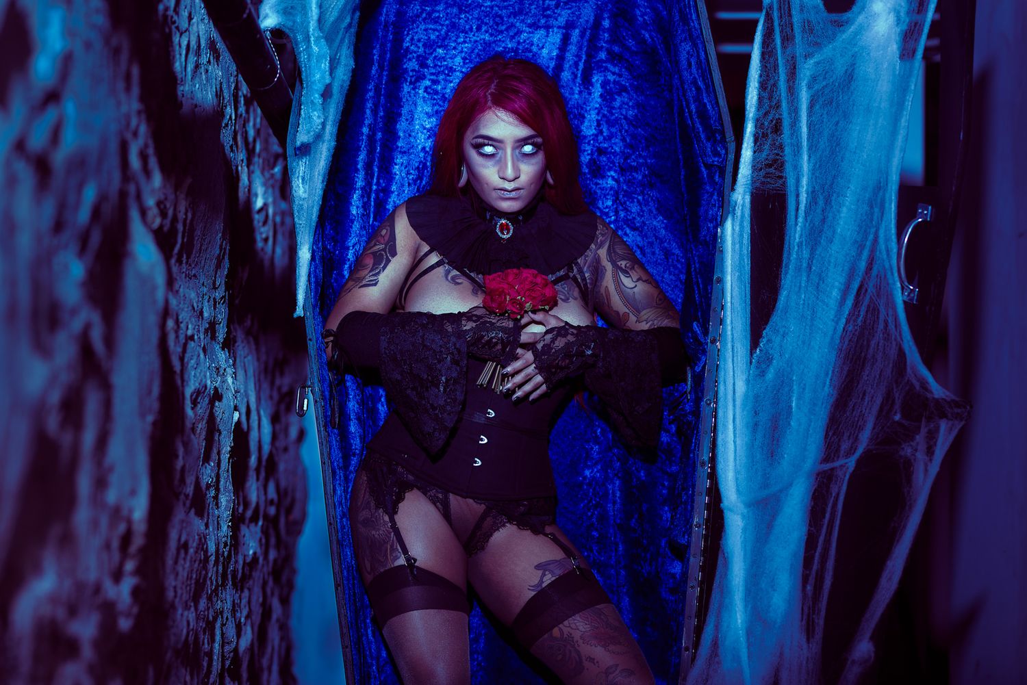 Gothic themed boudoir photo with blue lighting and dramatic shadows.