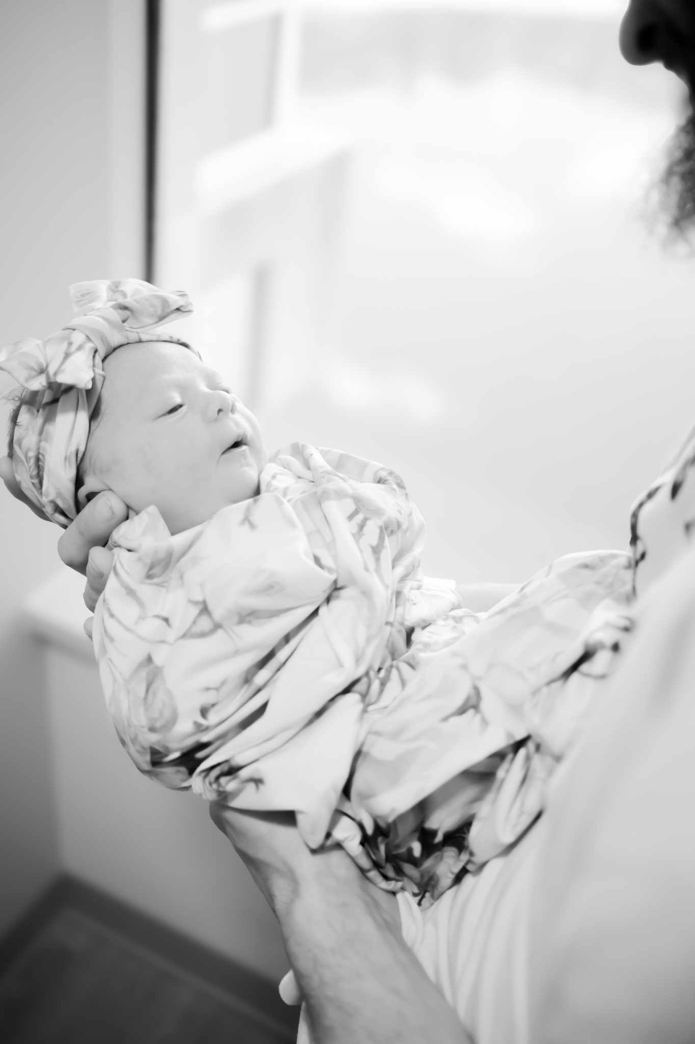Black and white photo of a mother holding her newborn wrapped in a receiving blanket.