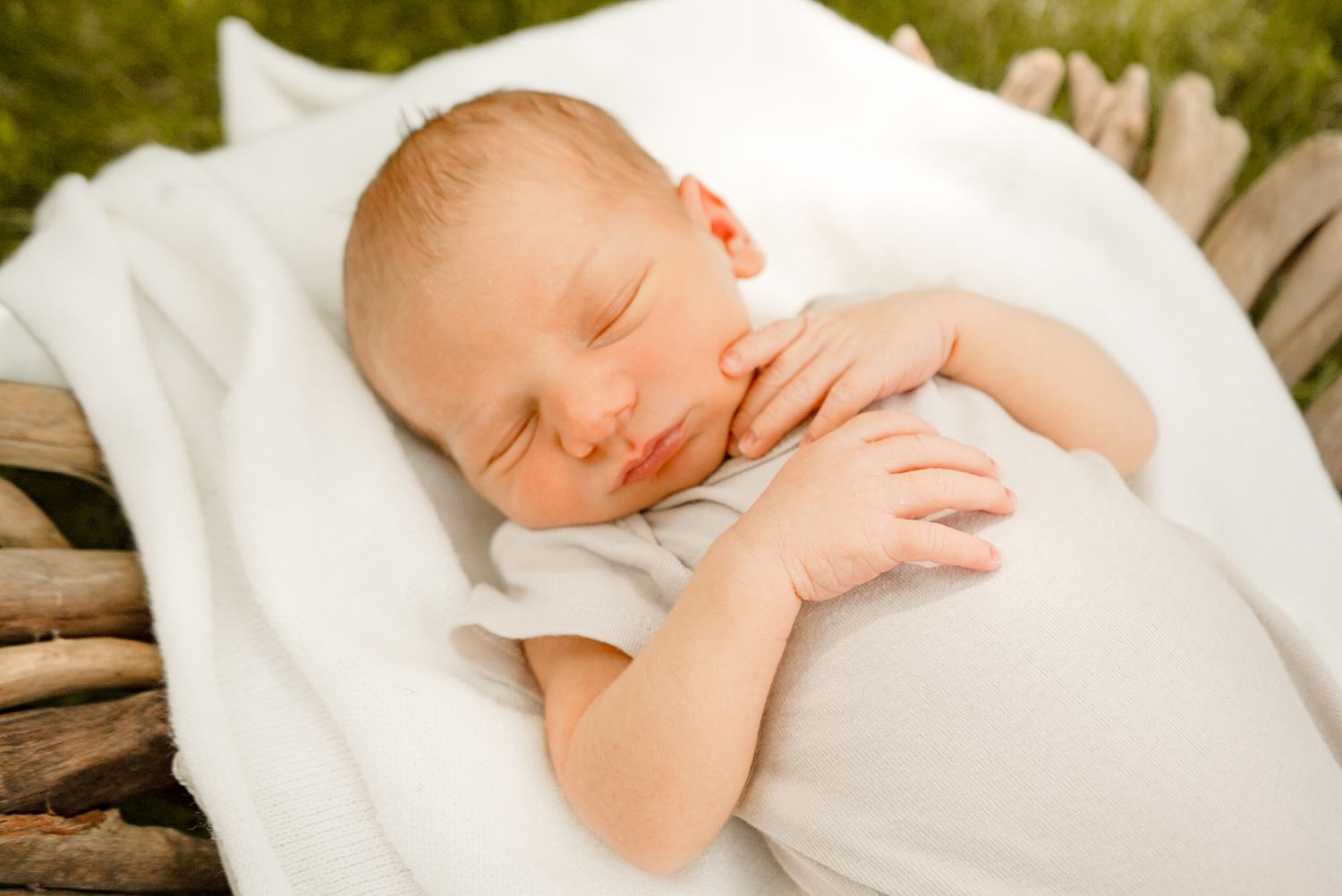 Tranquil newborn sleeps soundly on white blanket with rustic wooden elements in background.