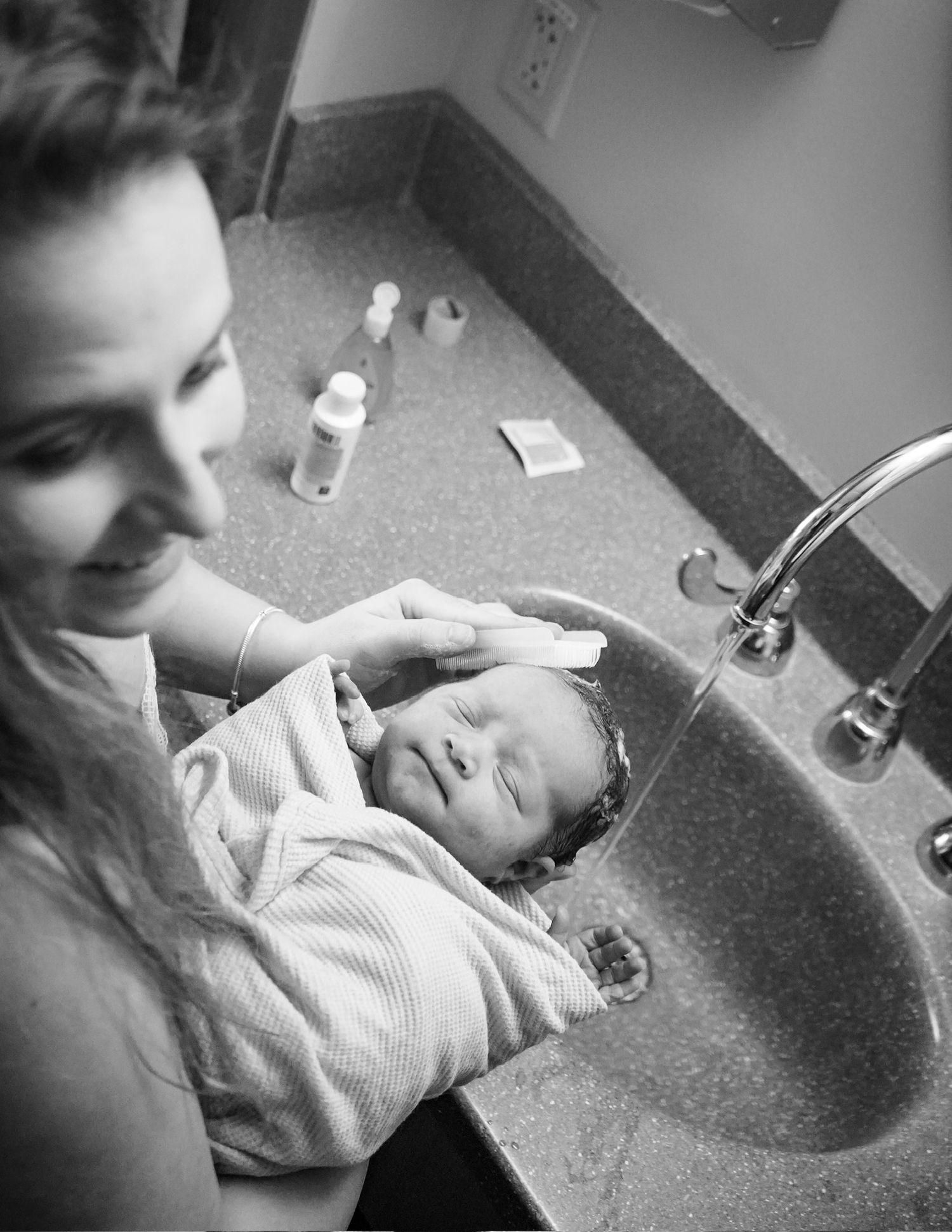 Monochrome photo showing a newborn receiving care in a hospital setting.