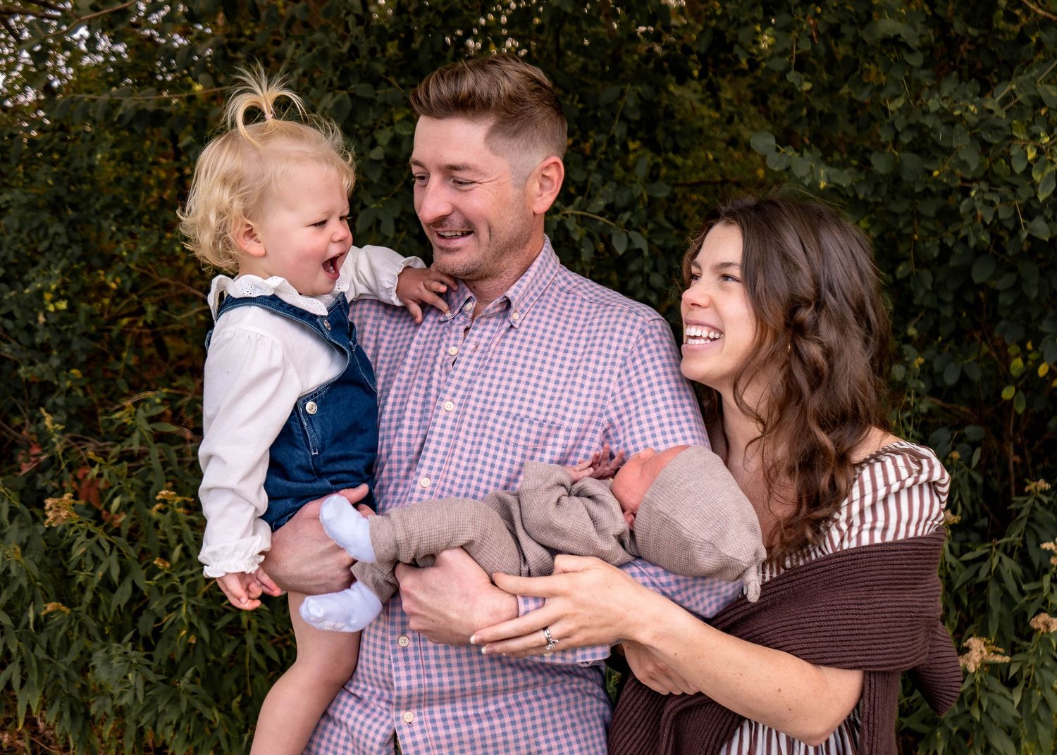 Family enjoying playful moments together outdoors against natural background.