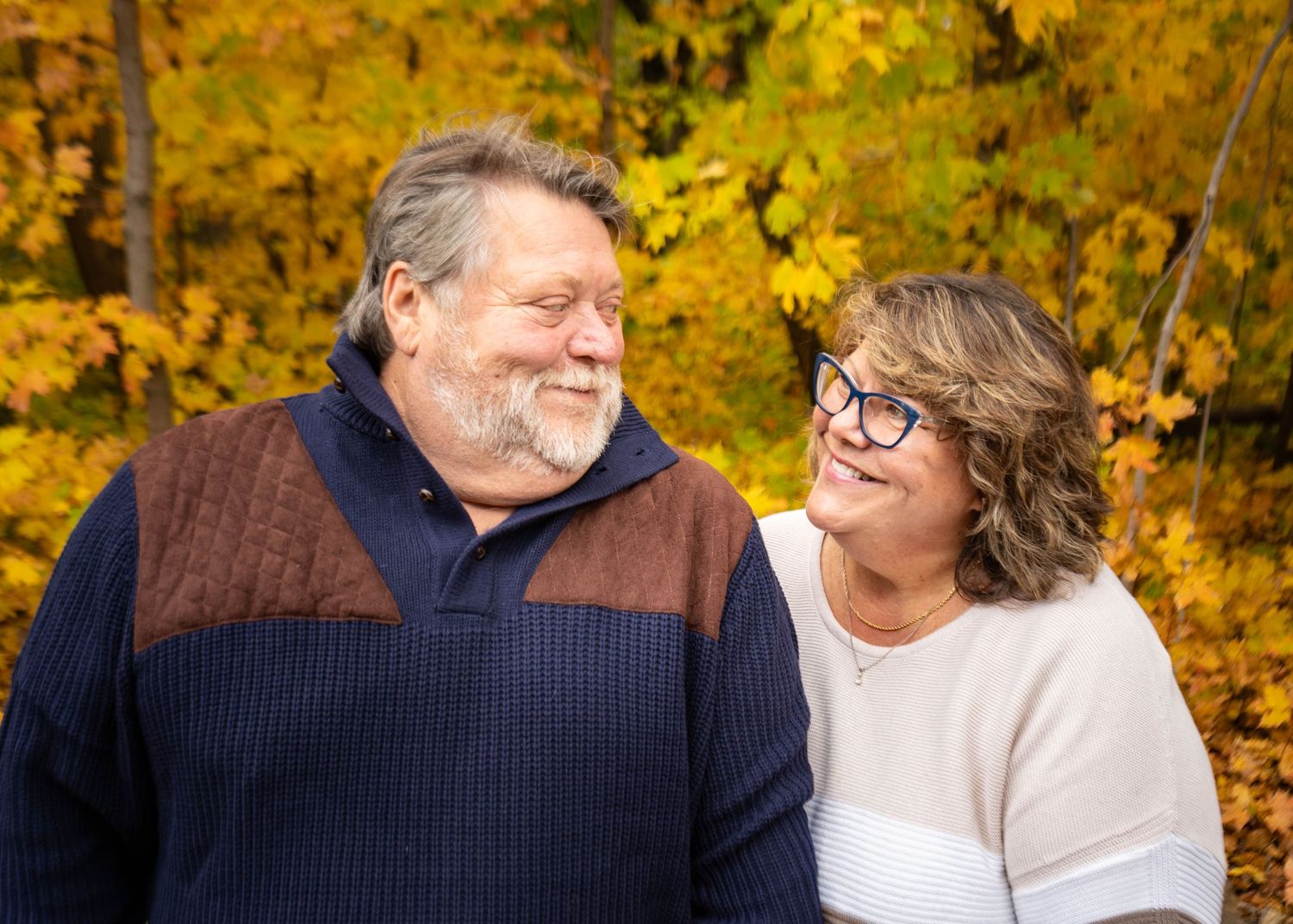 Couple sharing a romantic moment outdoors in autumn with golden yellow foliage in the background.