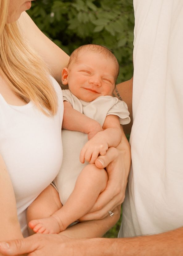 Tender moment showing hands cradling a peaceful sleeping baby in soft lighting.