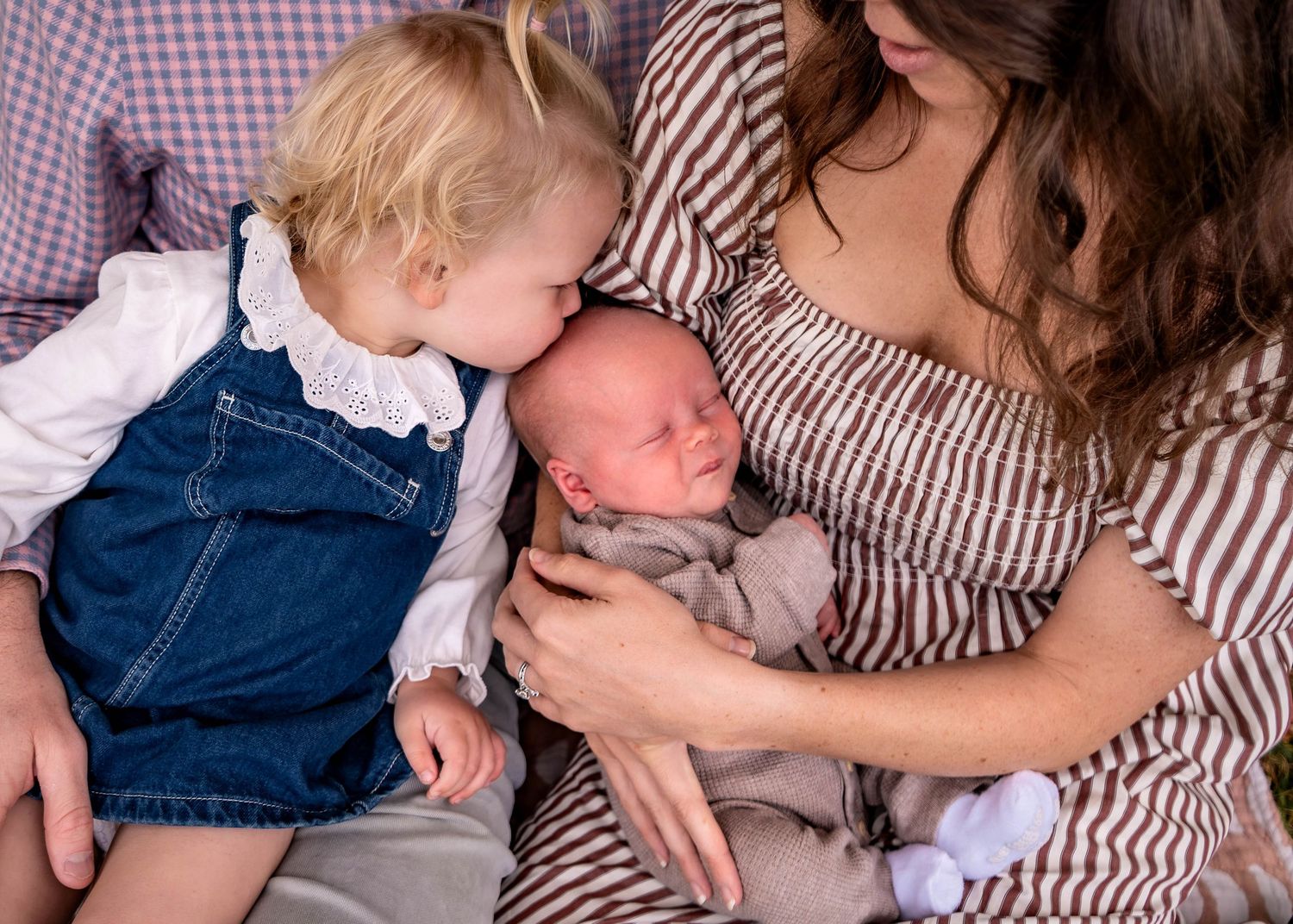 Sweet family interactions on cozy striped blanket during outdoor photoshoot.