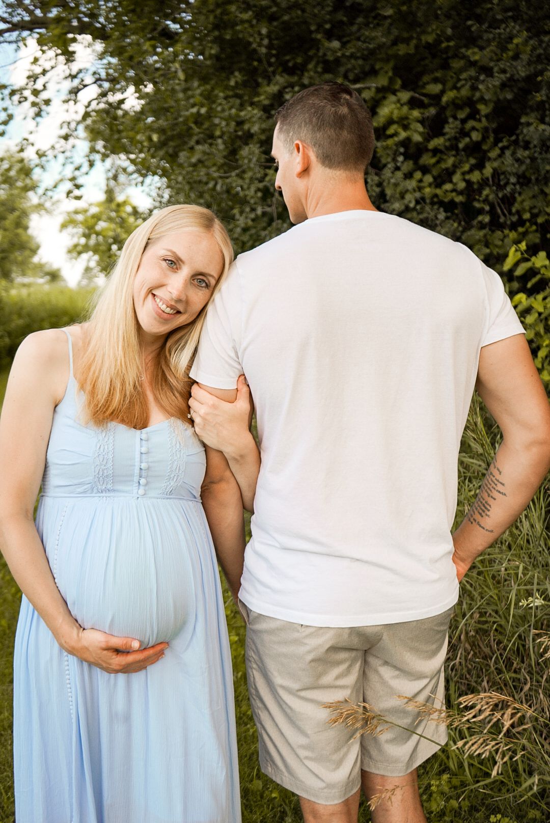 A pregnancy photoshoot in a lush garden setting with natural lighting.