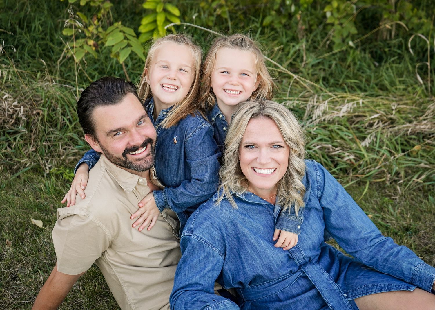 Family group lounging together on grass during outdoor photo session.