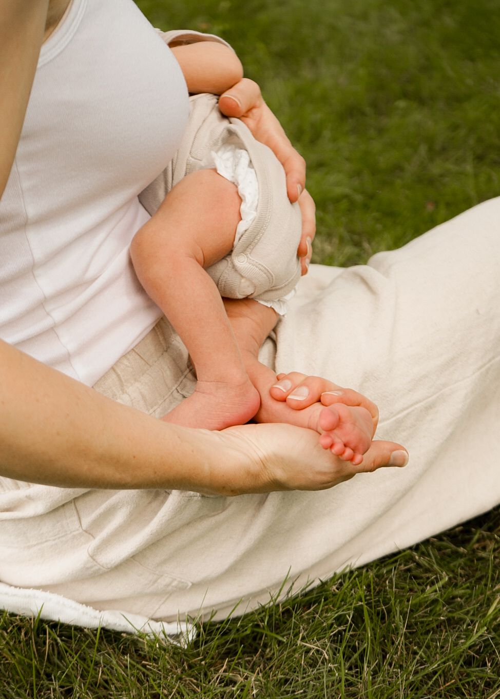 Close-up shot of baby feet resting on white fabric against green grass background.