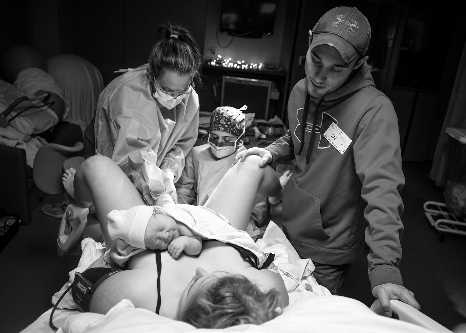 Medical professionals working together during patient care in dimly lit hospital room.