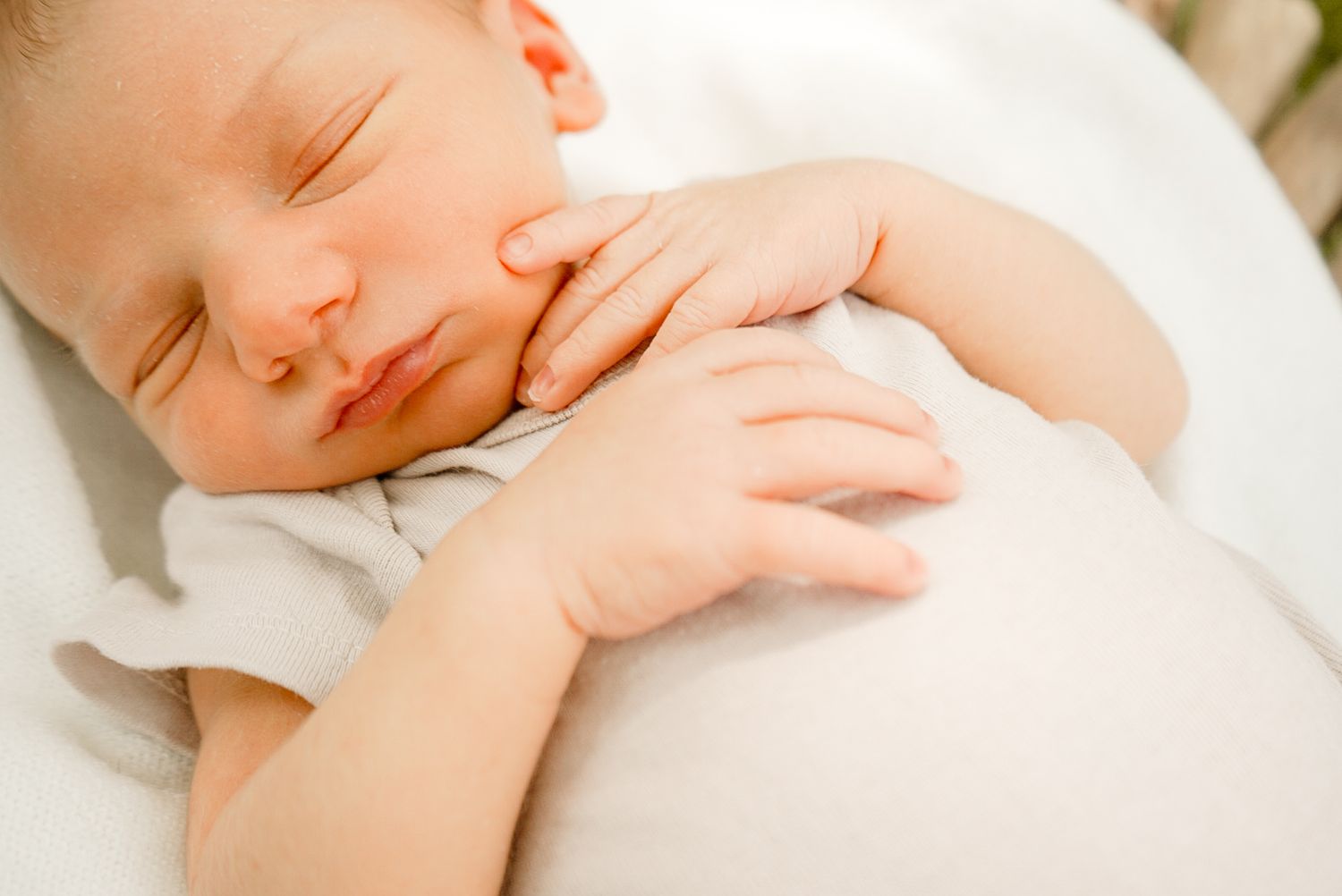 Gentle hands performing soothing massage strokes on a sleeping newborn baby.