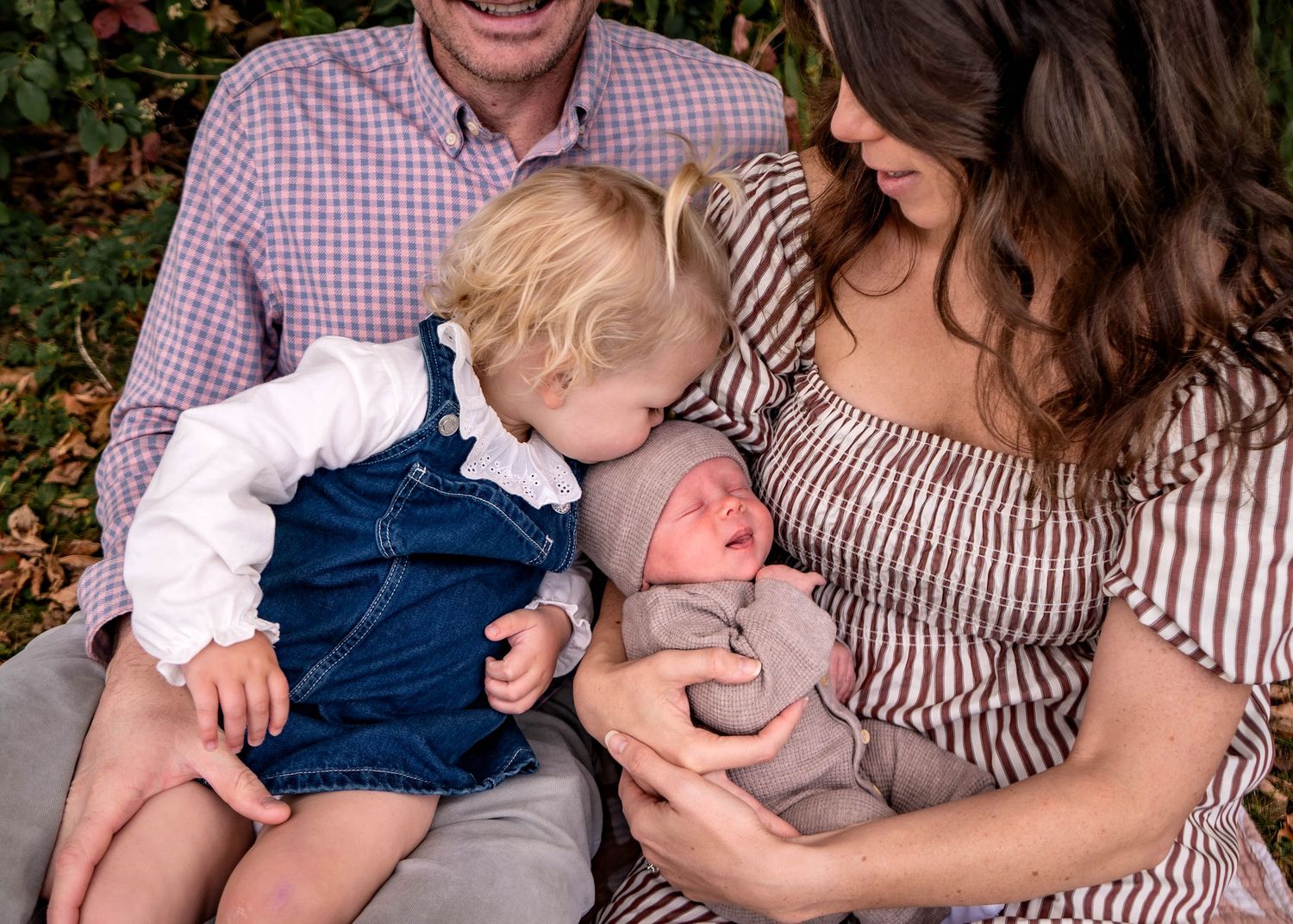 A tender moment captured outdoors showing playful interaction between parent and child in casual attire.