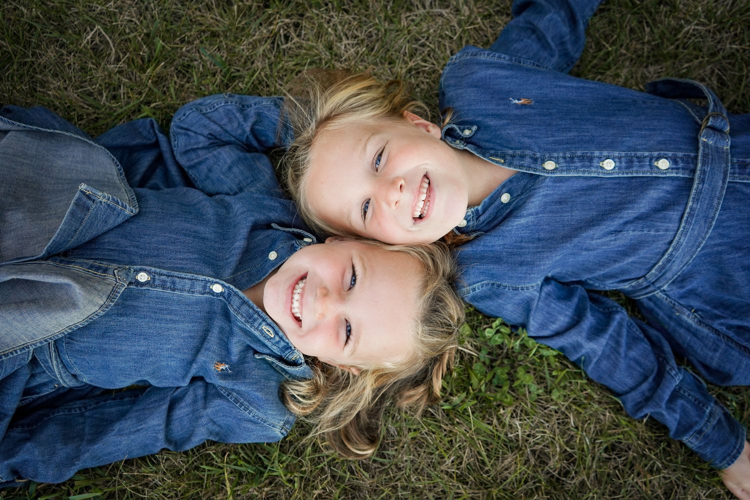 Group portrait of people in denim clothing relaxing on grass outdoors.