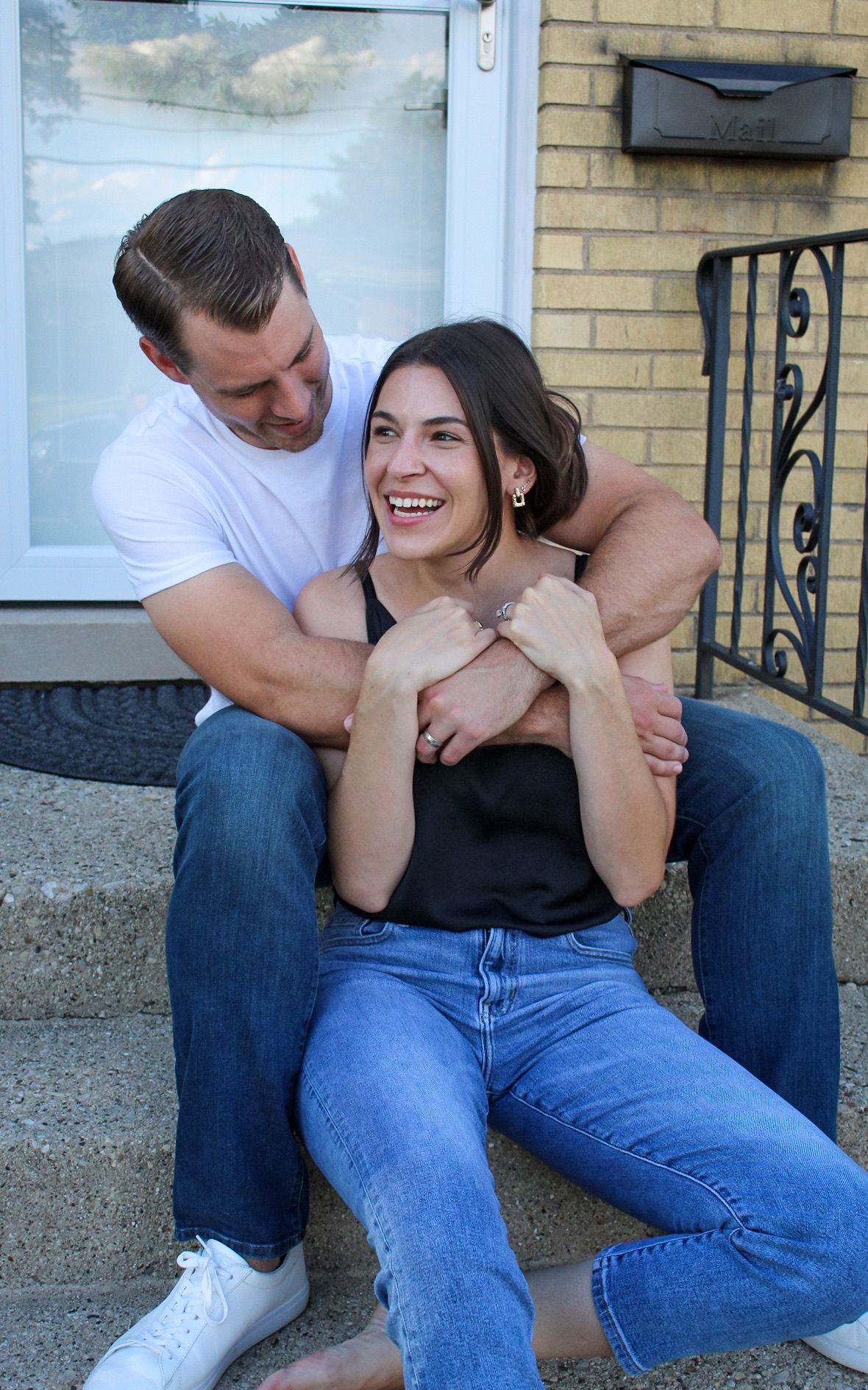 Casual couple sharing playful moment while sitting on concrete steps.