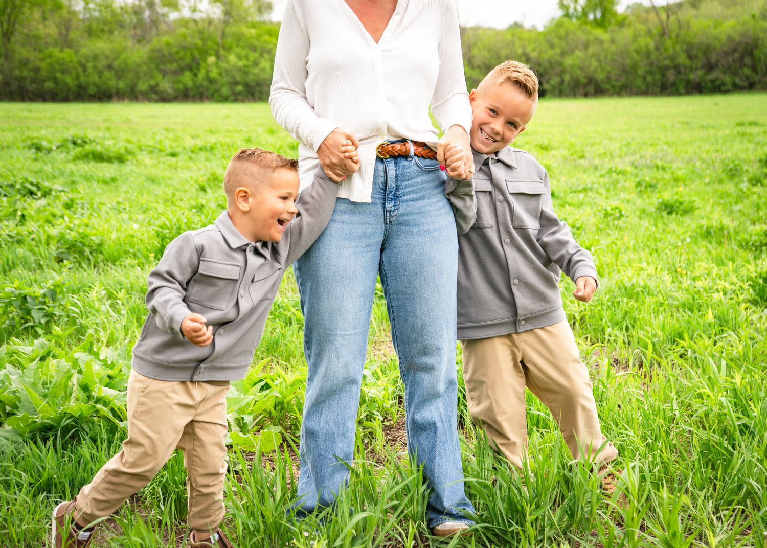 Family walking and playing together in a green grass field on a sunny day.