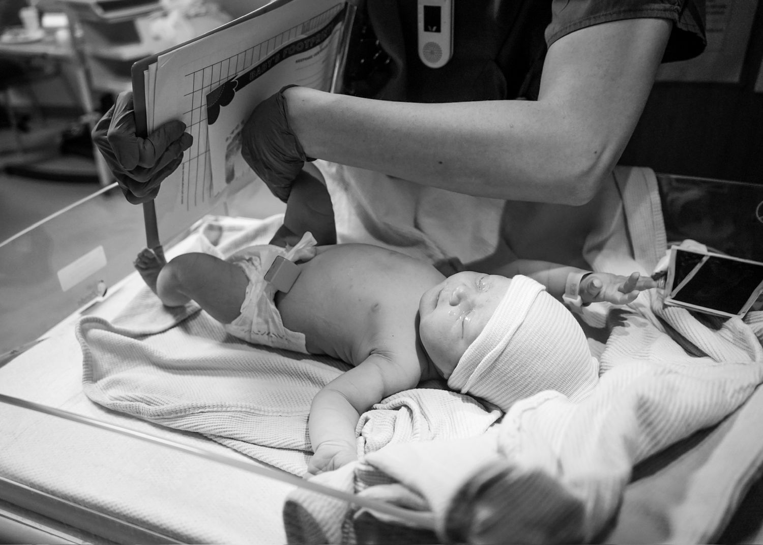 Medical team performing newborn examination in black and white.