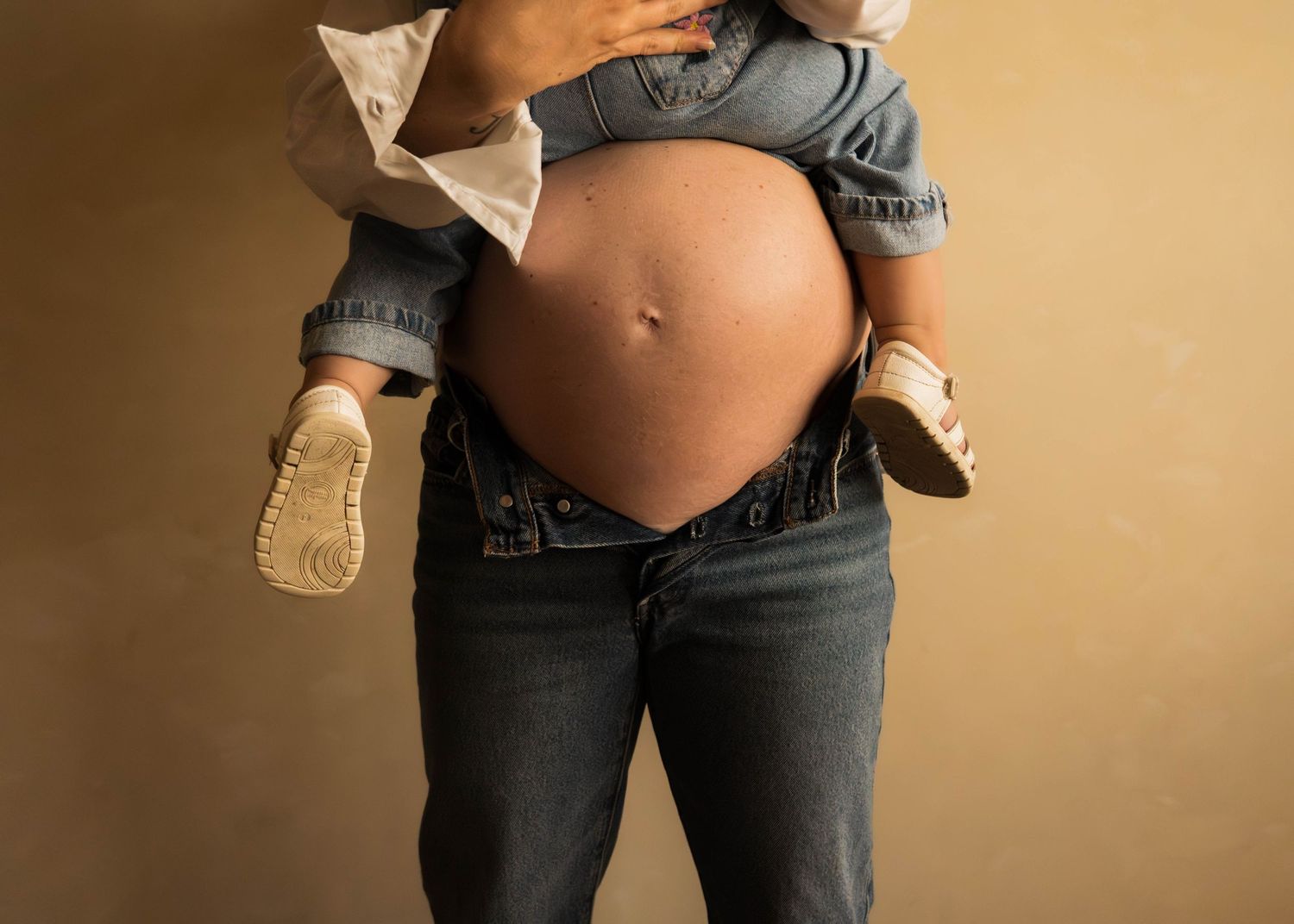 Maternity photo series capturing pregnancy in casual white shirt and jeans.