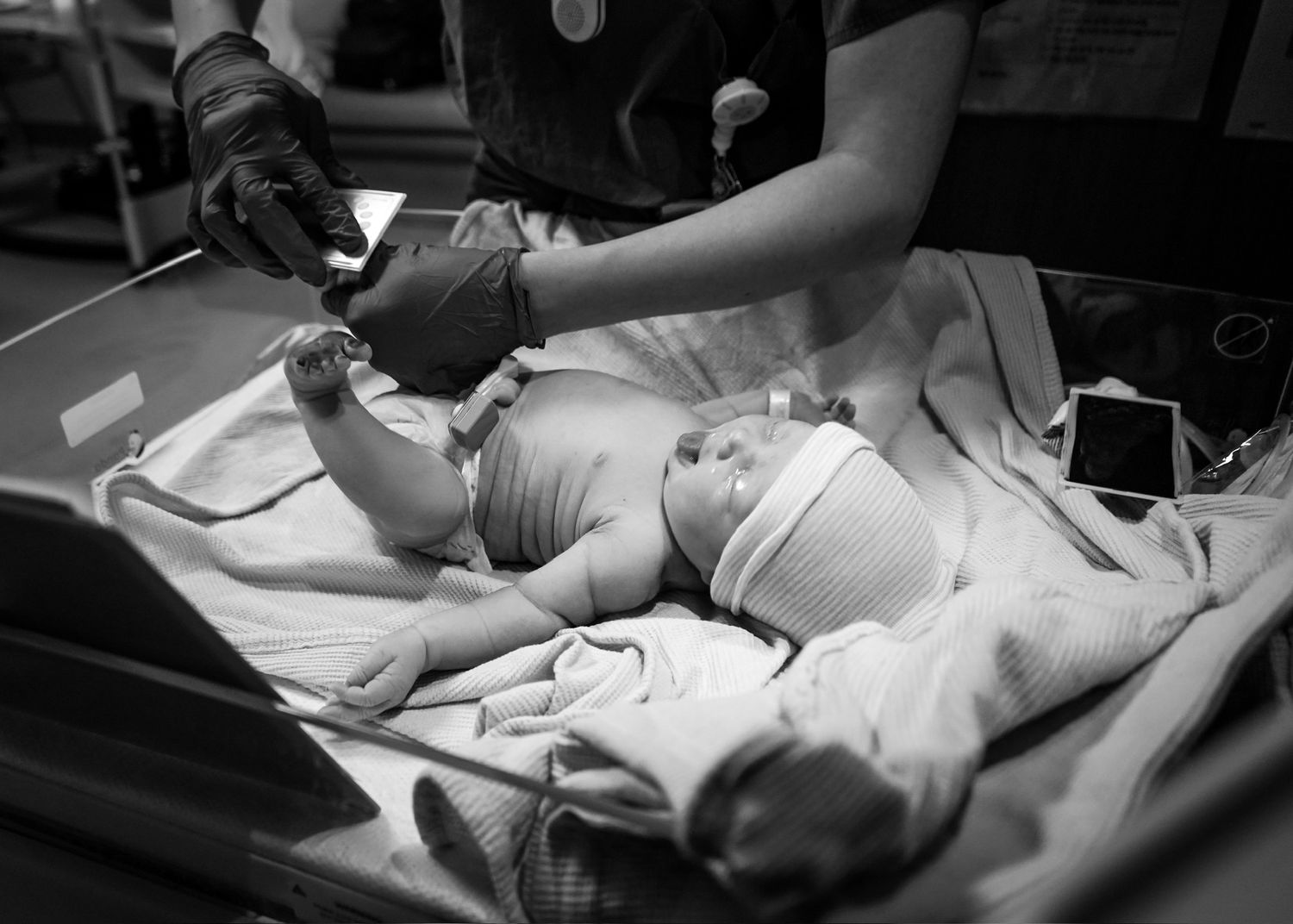 Medical staff examining newborn baby on hospital table under bright lights.