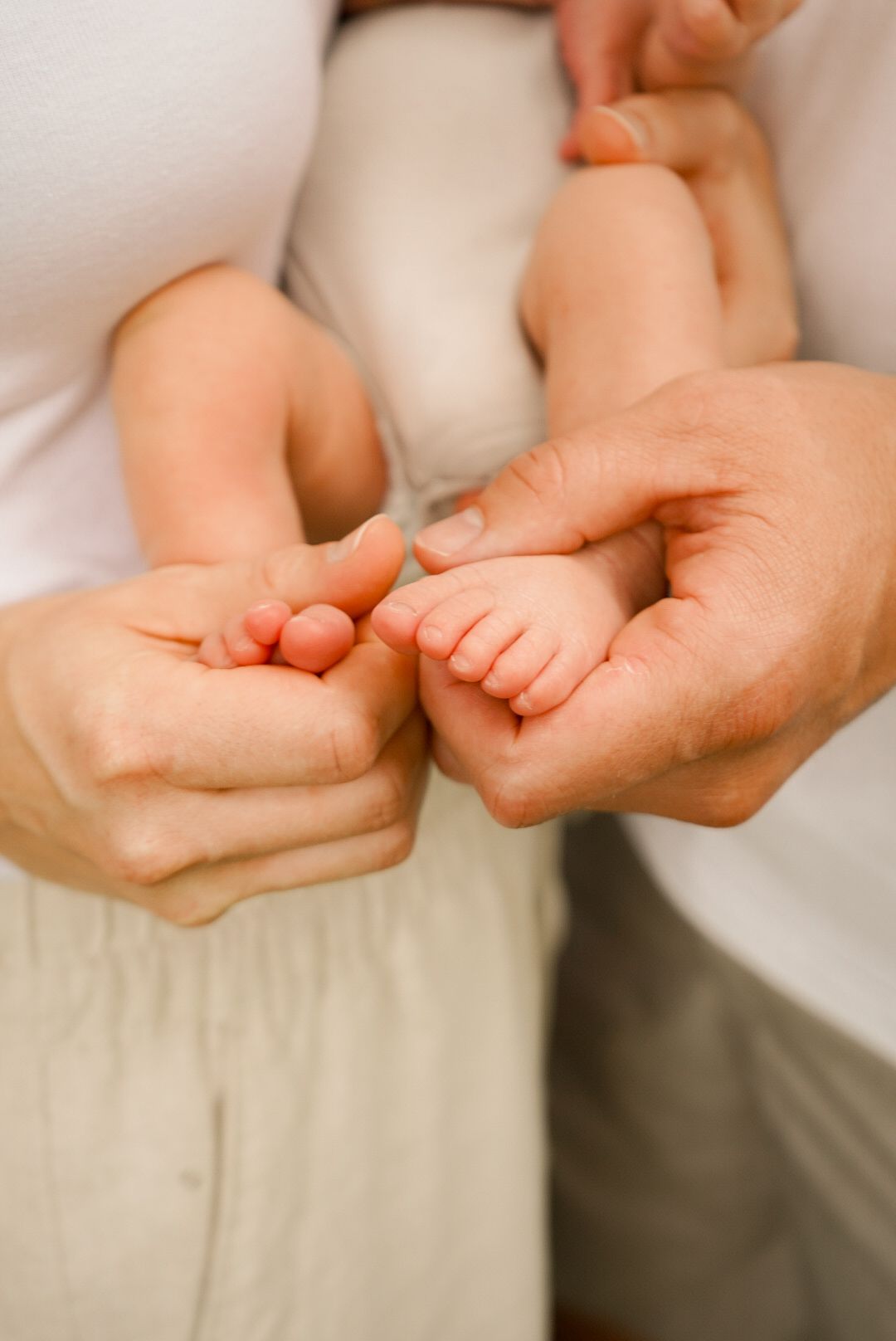 Delicate close-up of tiny baby feet being held in gentle hands.