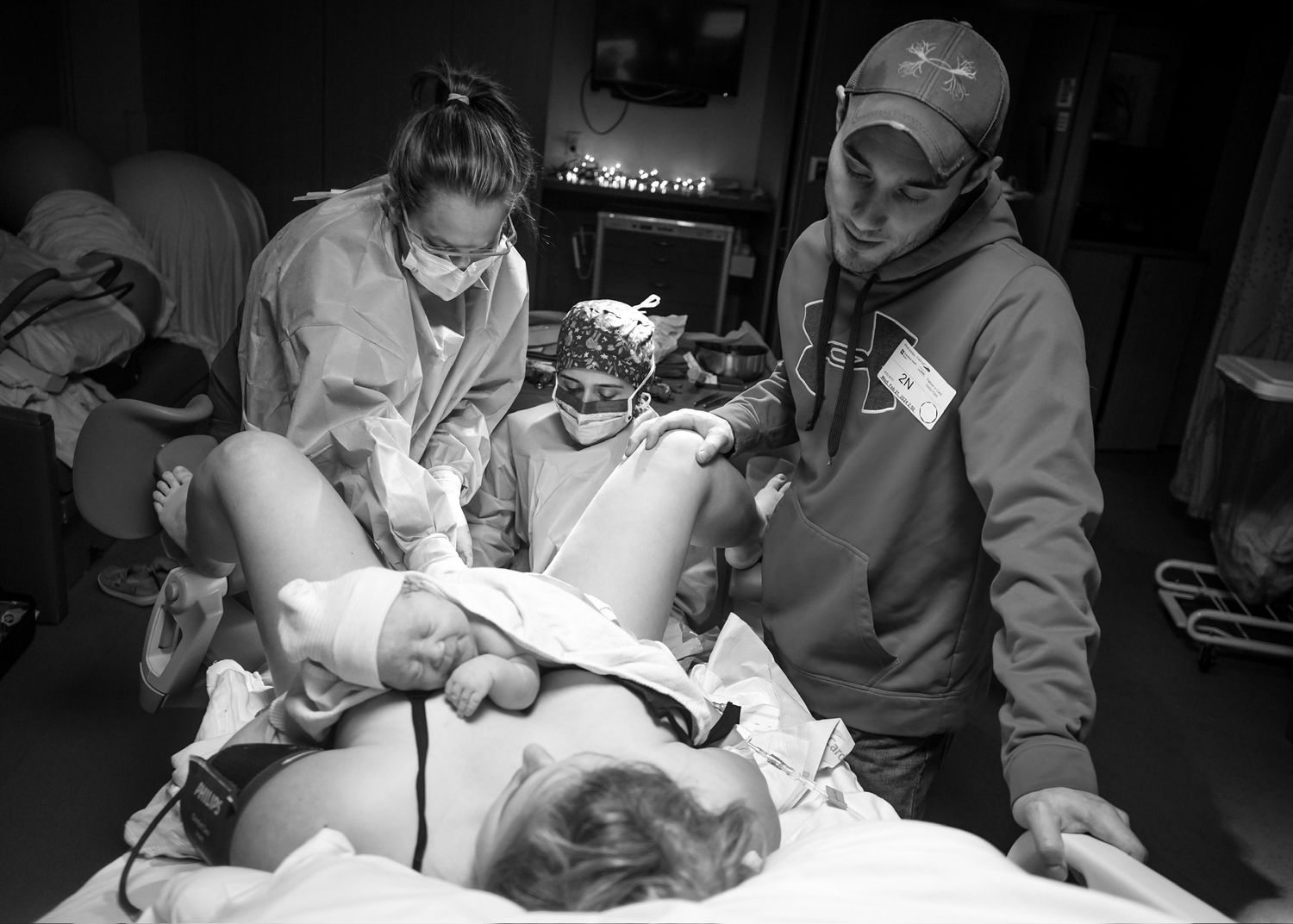Black and white image of medical staff performing procedure in hospital room.