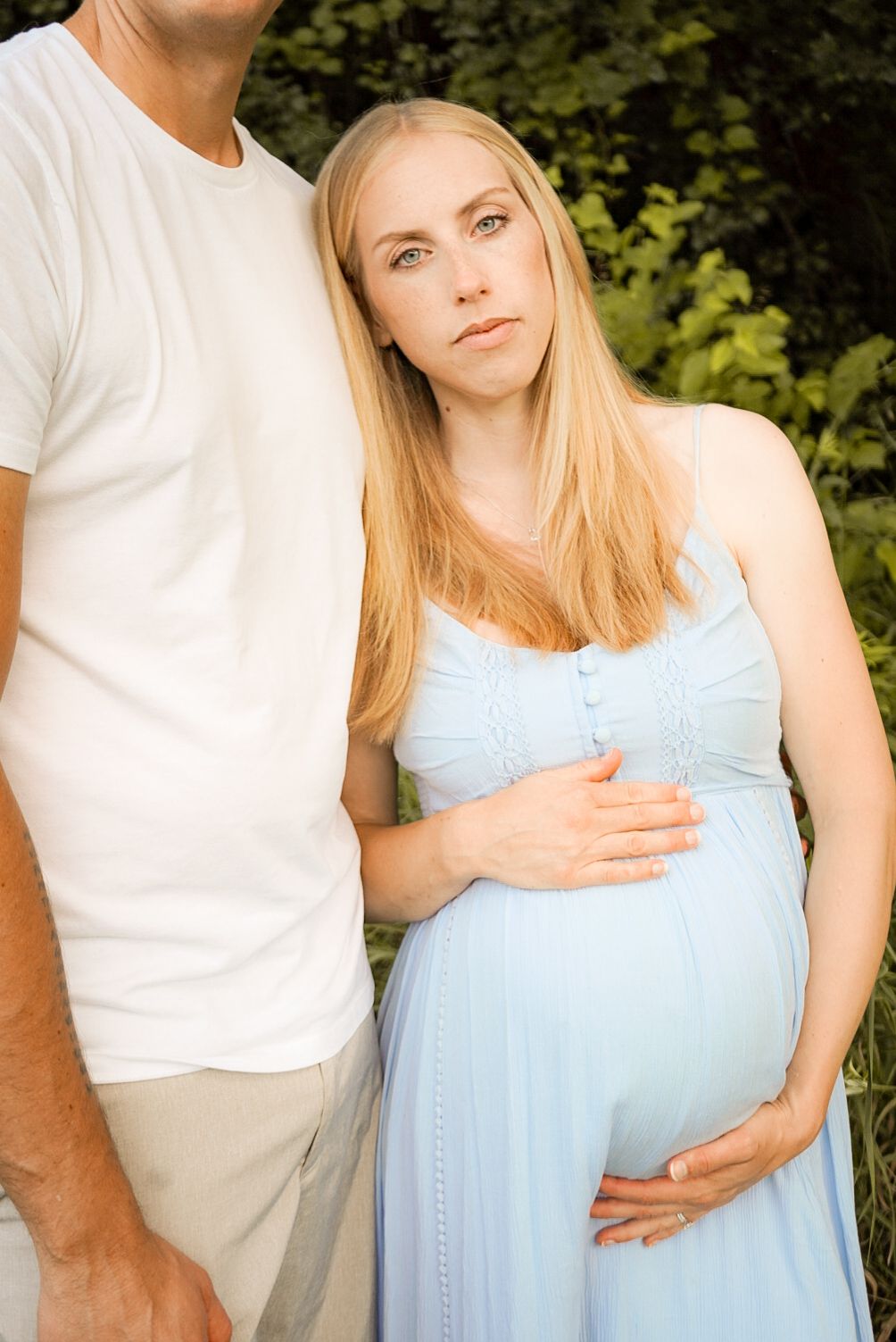 An expectant couple shares intimate moments during an outdoor maternity photo session.