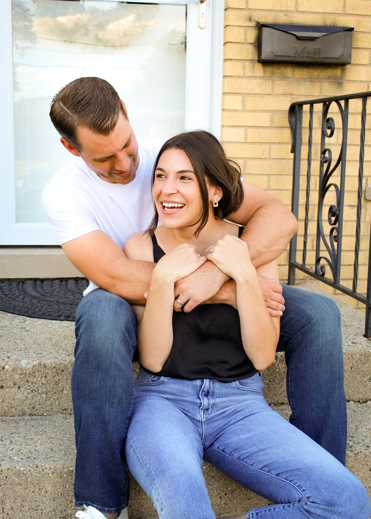 Candid moments between couple sitting on outdoor steps with architectural details.