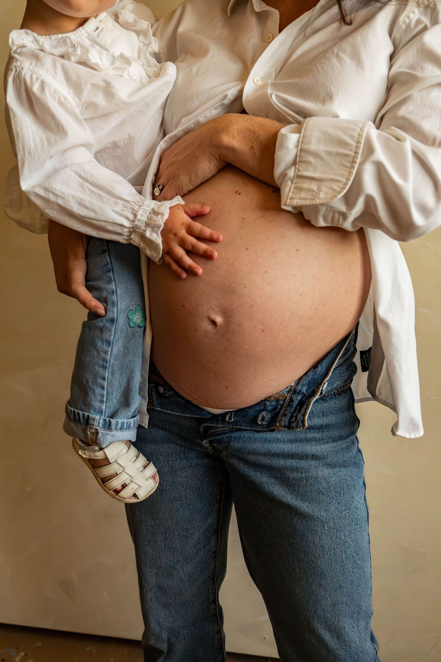 A series of maternity photos showing a growing baby bump in jeans and white shirt.