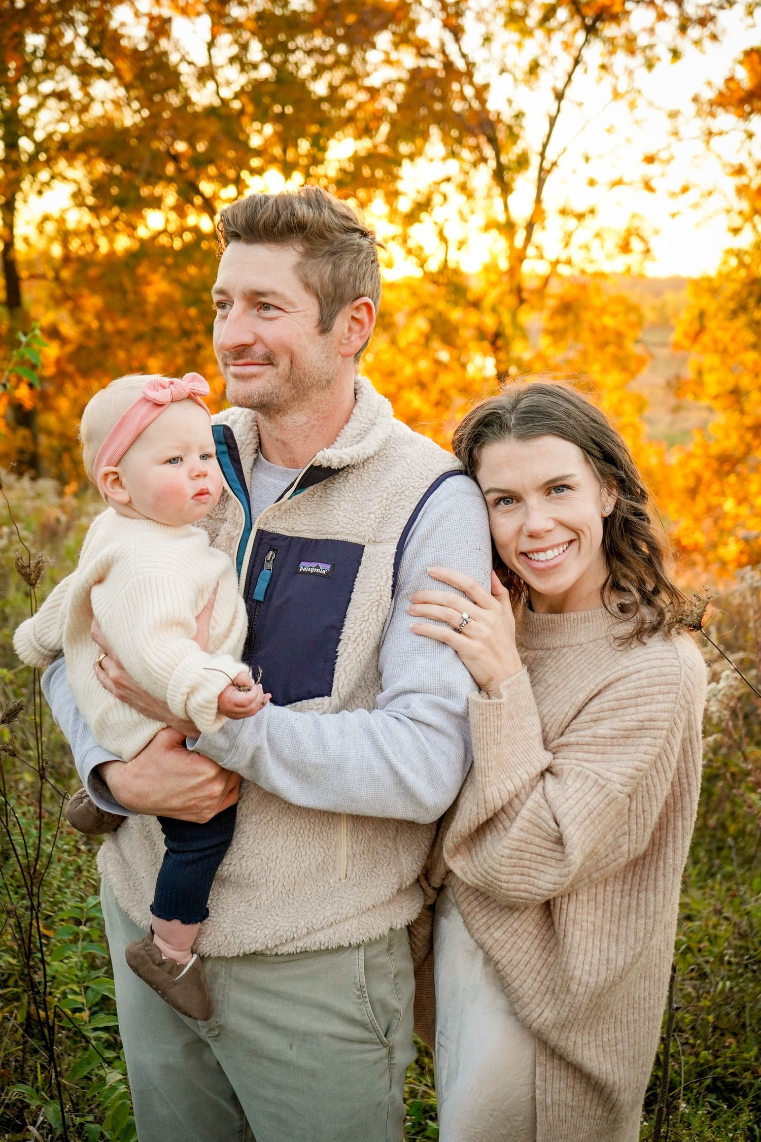 Happy family sharing laughter and cuddles in fall setting with golden sunlight.
