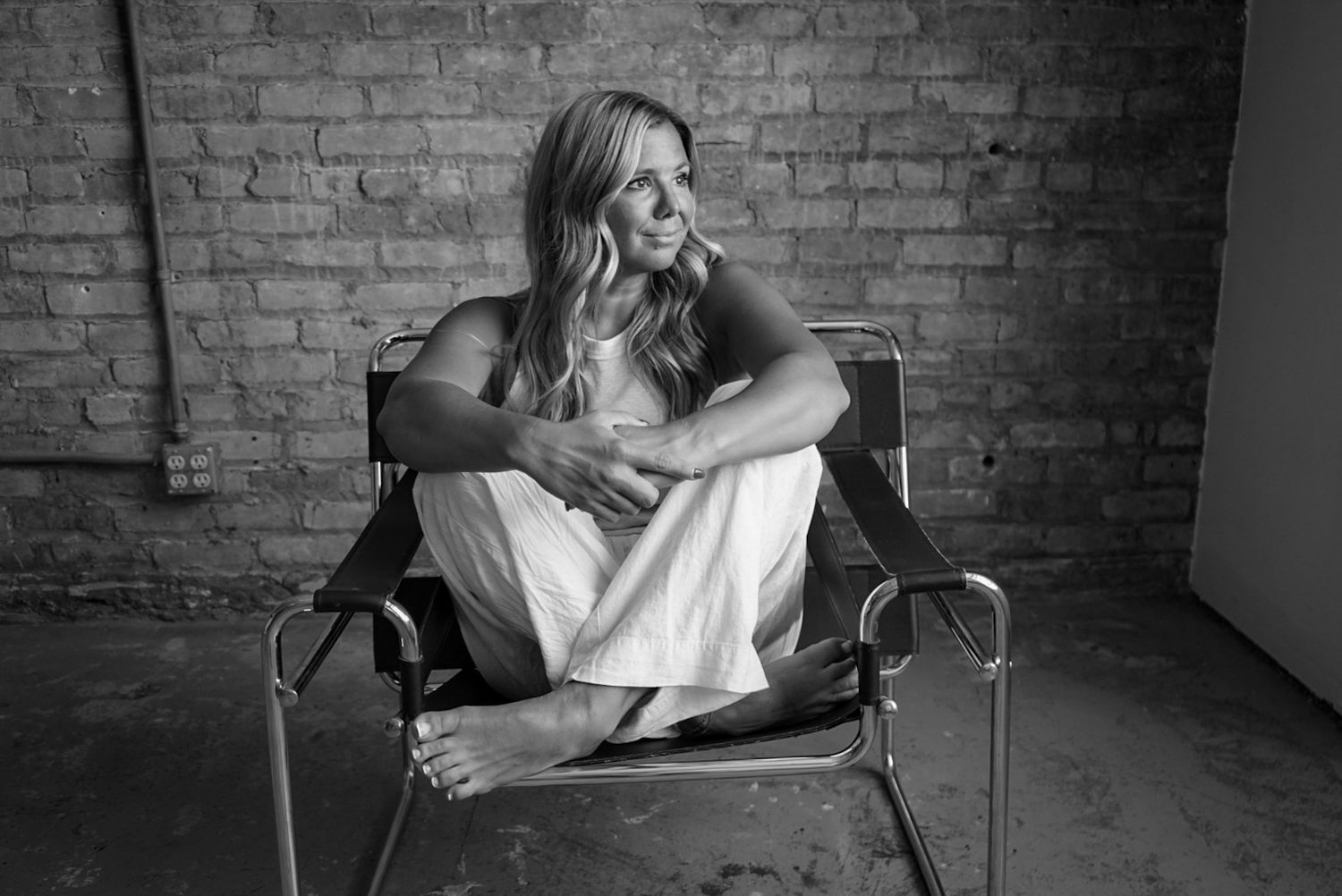 Black and white maternity series showing poses against an industrial brick backdrop.