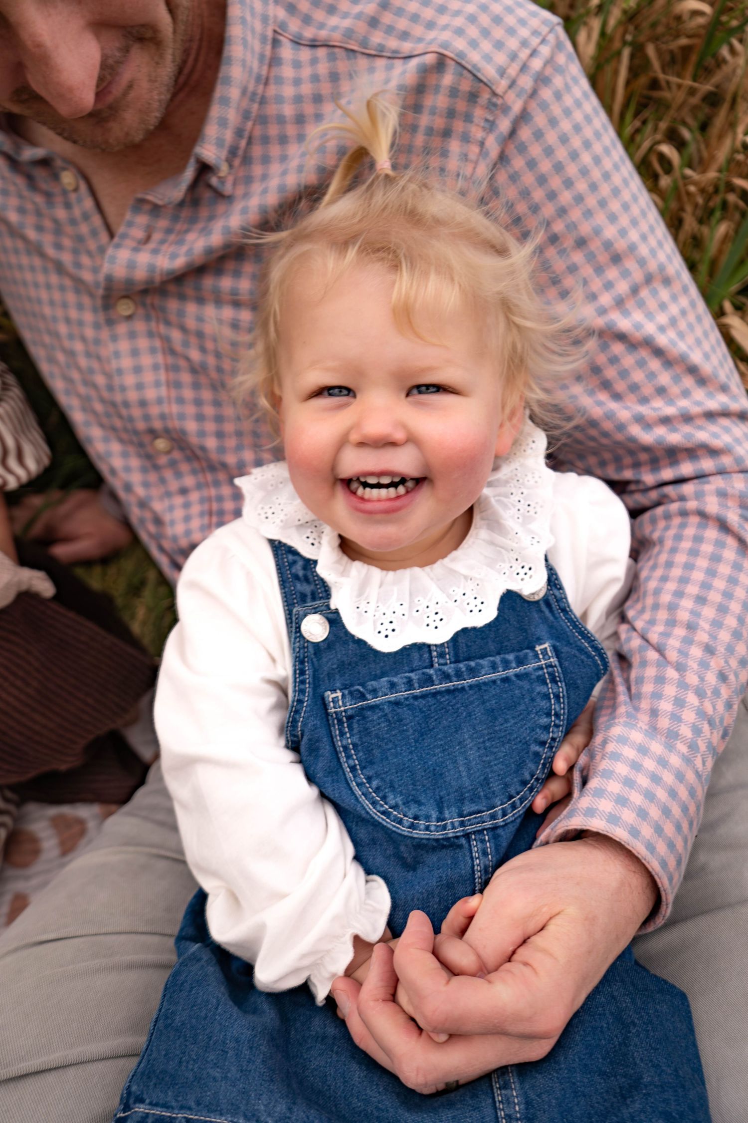 A series of candid shots showing a toddler in denim overalls and white collar blouse smiling brightly.