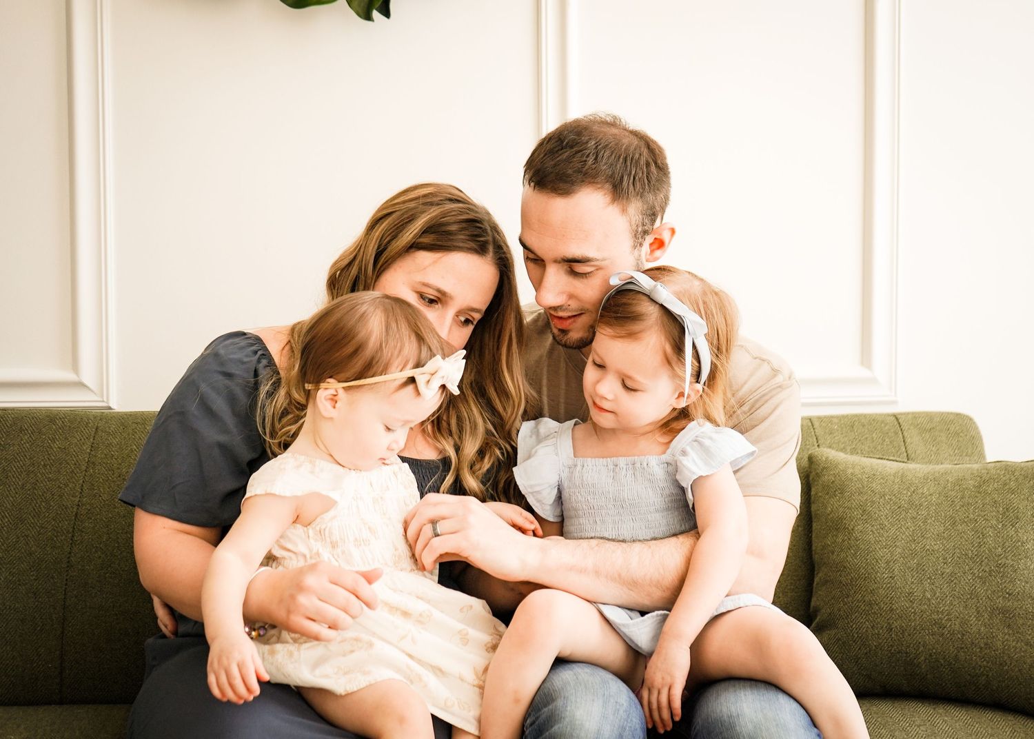 Intimate family gathering on grey couch in neutral-toned living room.